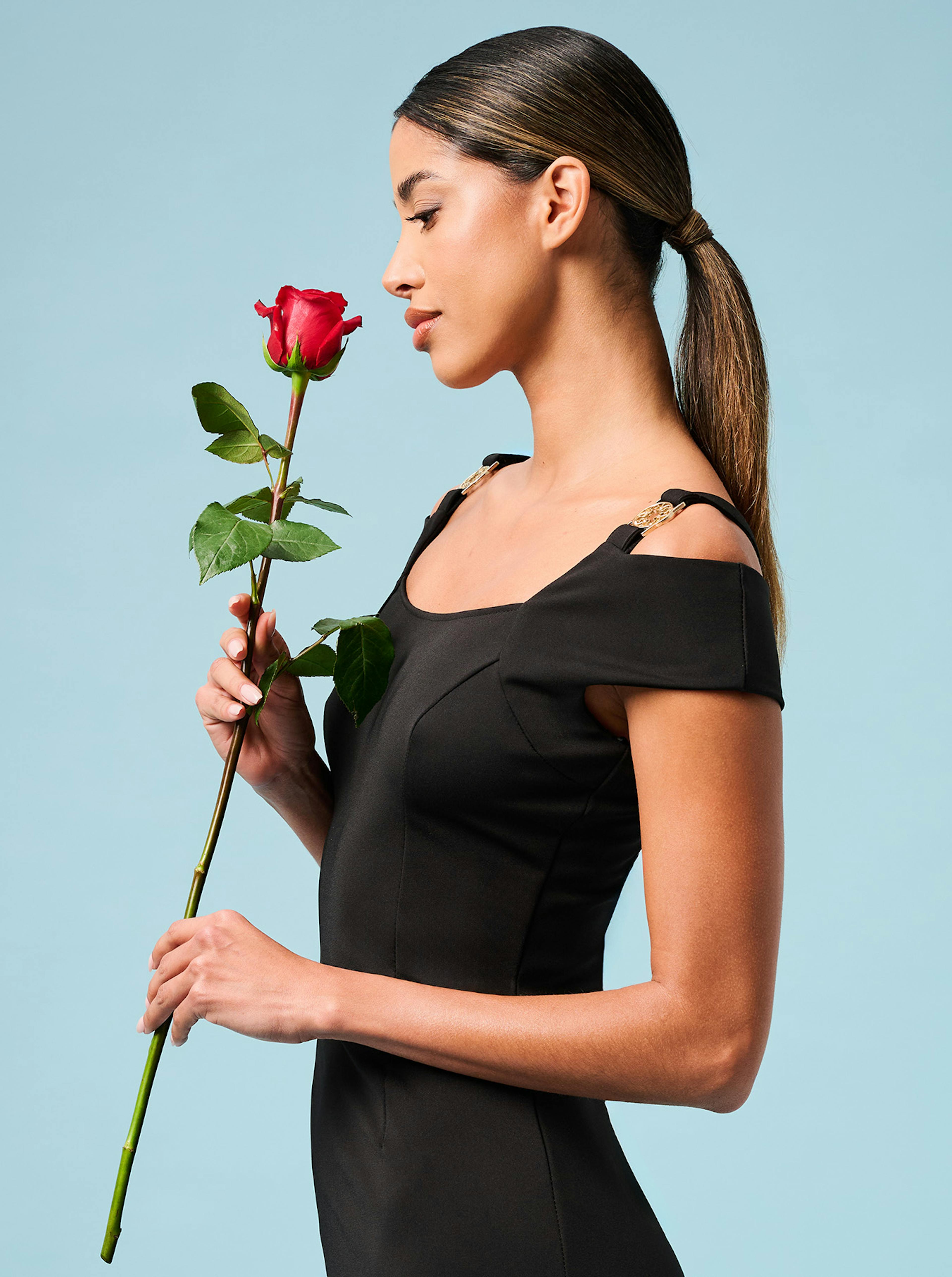 A stylish woman wearing a black dress and a rose