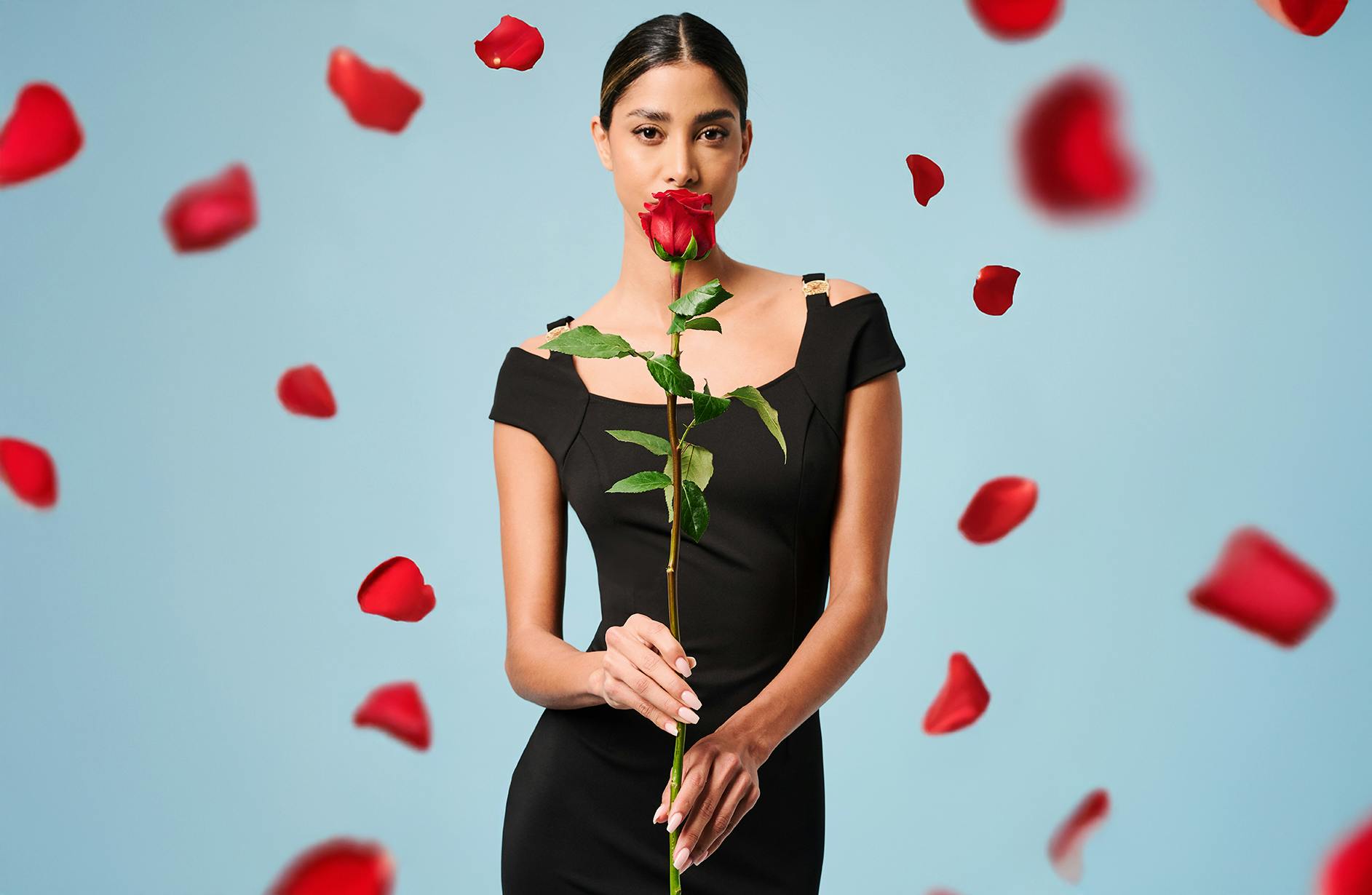 A sophisticated woman in a black dress with rose petals