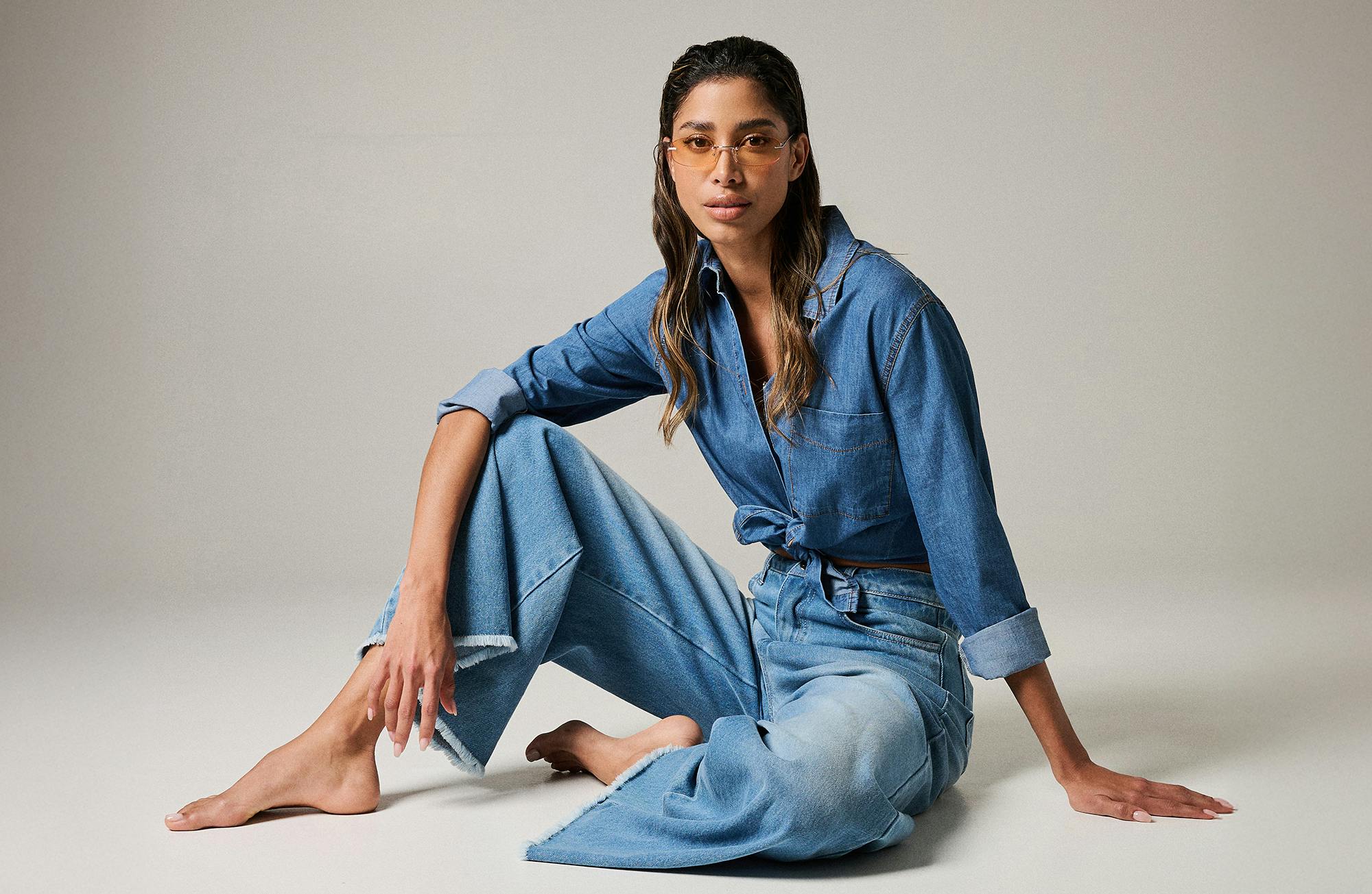 A woman dressed in blue jeans sits on the floor