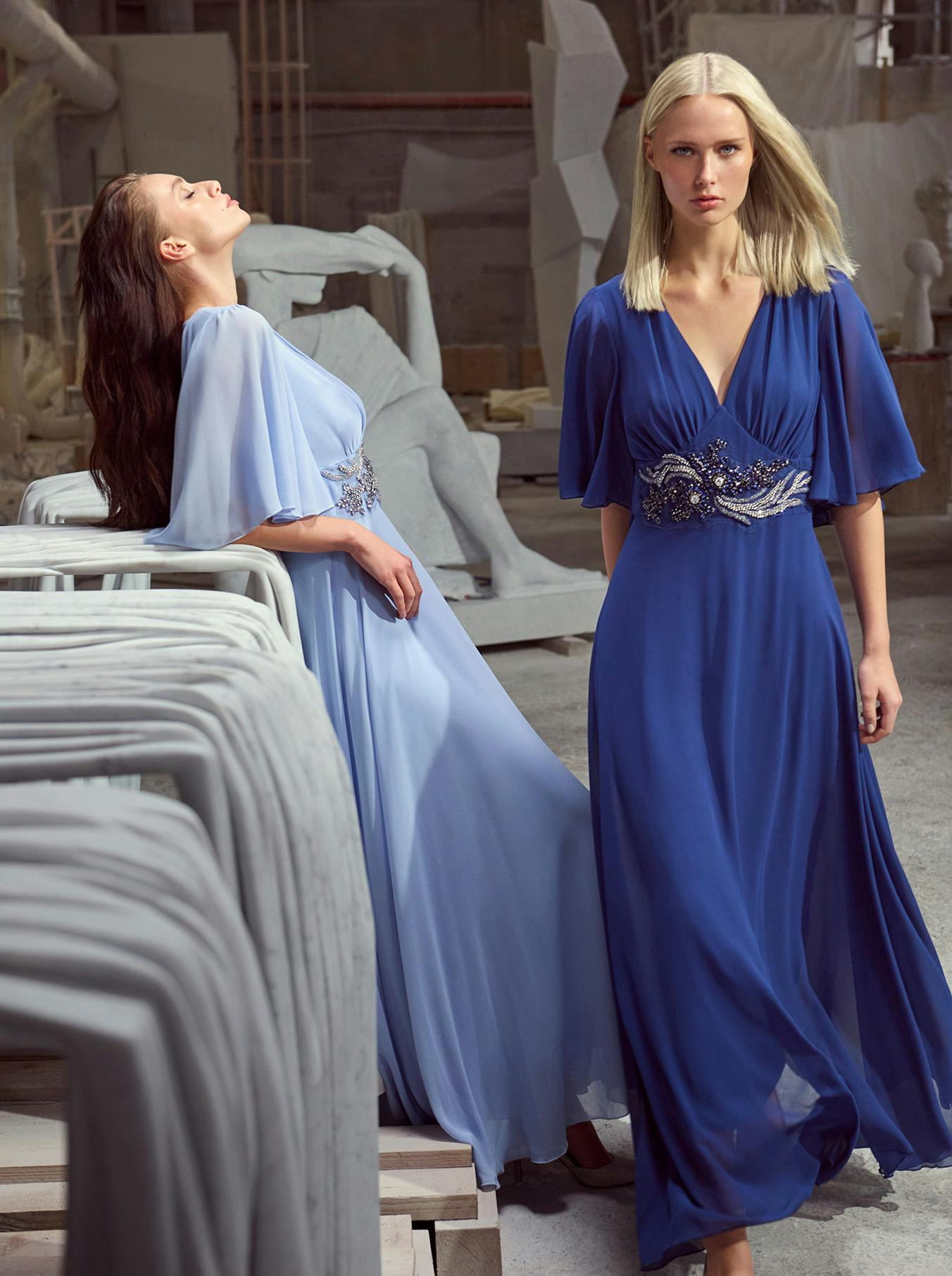 Two elegantly dressed women in flowing blue dresses