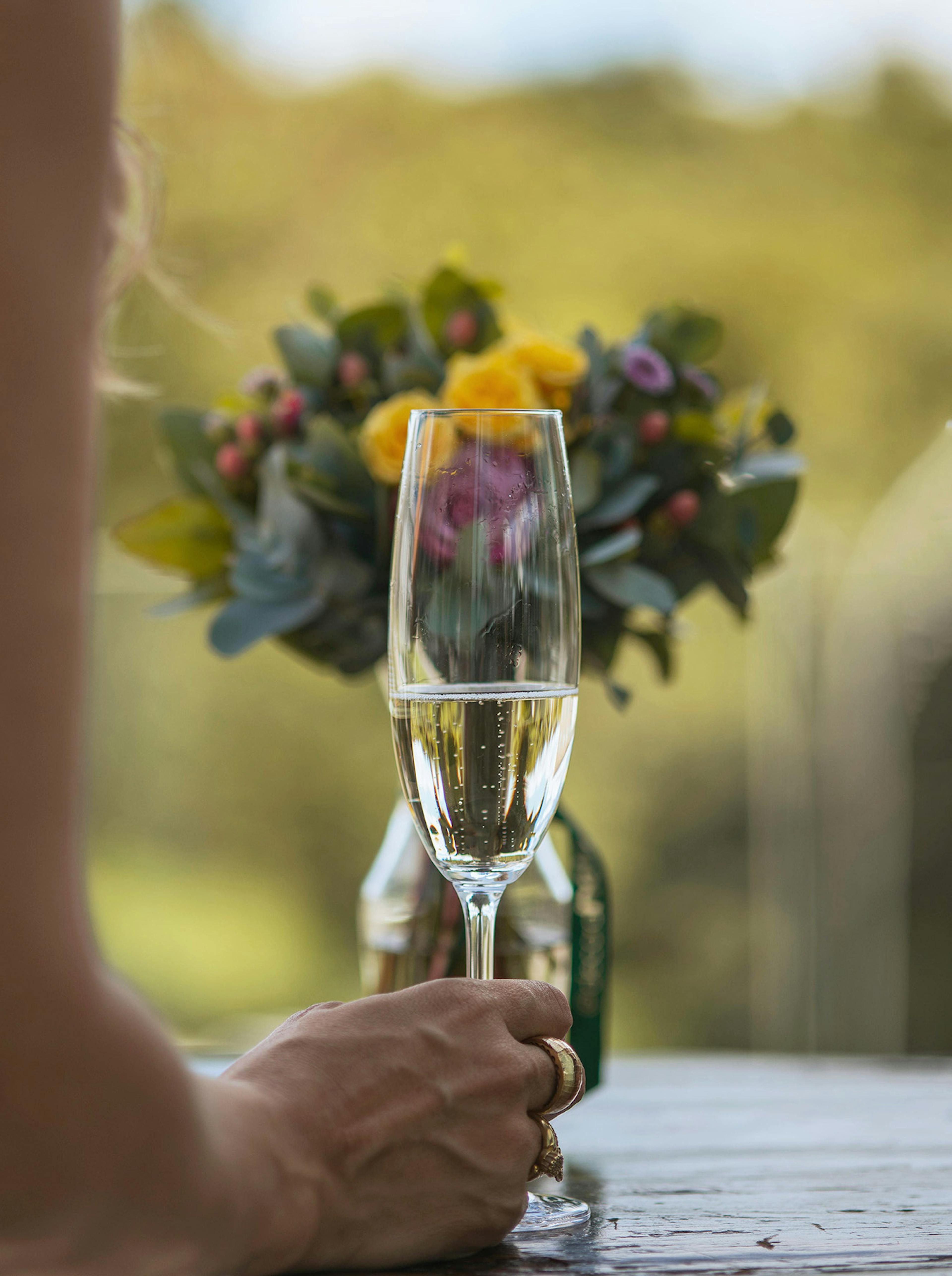 bicchiere di spumante con bouquet di fiori sullo sfondo