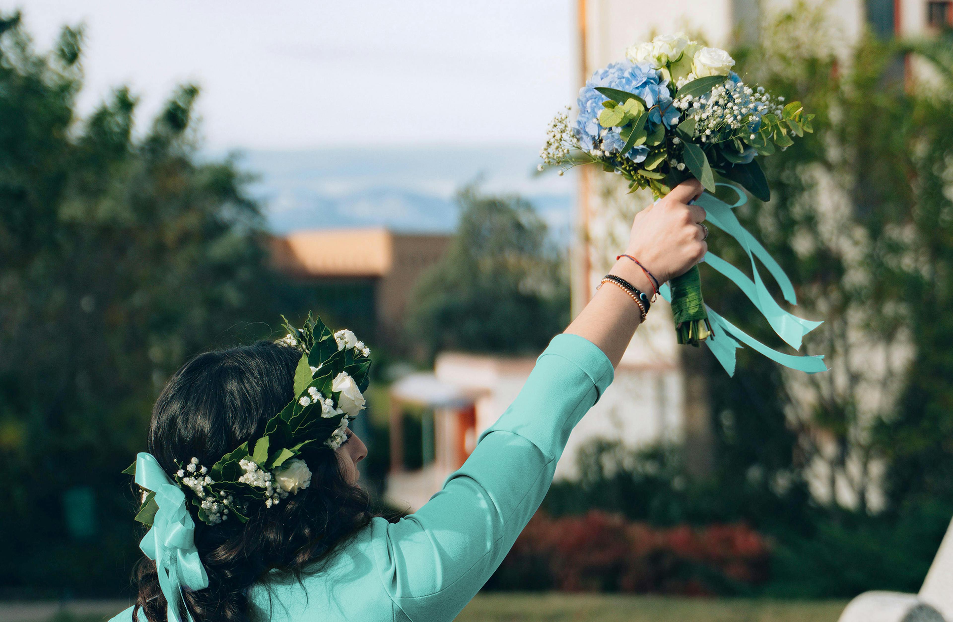 ragazza laureata con corona d'alloro in testa e mazzo di fiori in mano