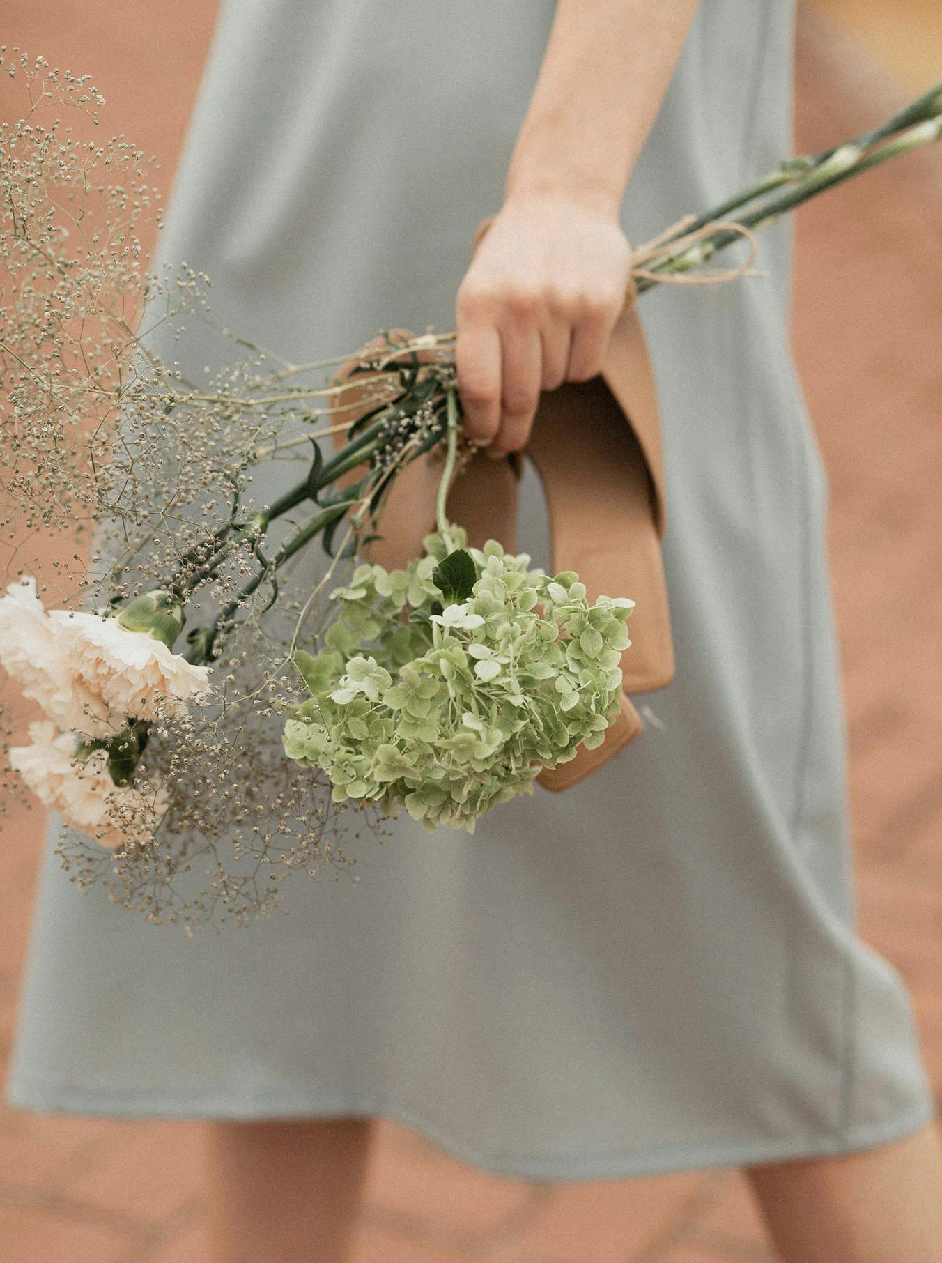 Donna che tiene in mano scarpe e fiori