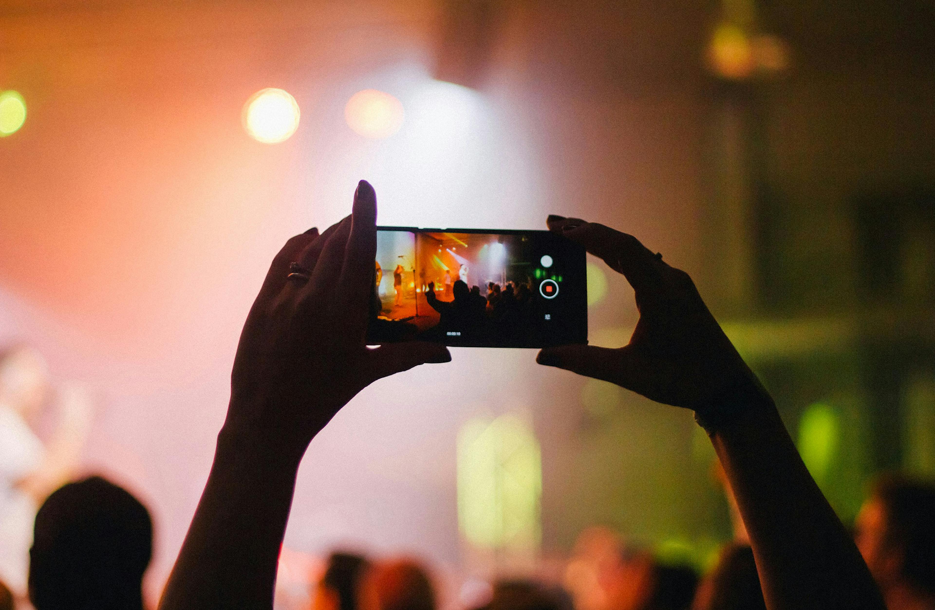 hands holding up a mobile phone to take a video