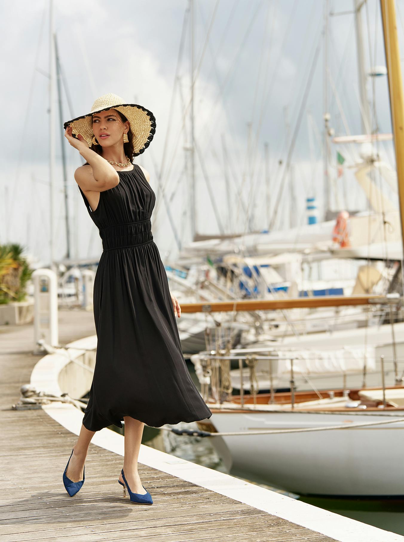 Modella con vestito nero e cappello di paglia