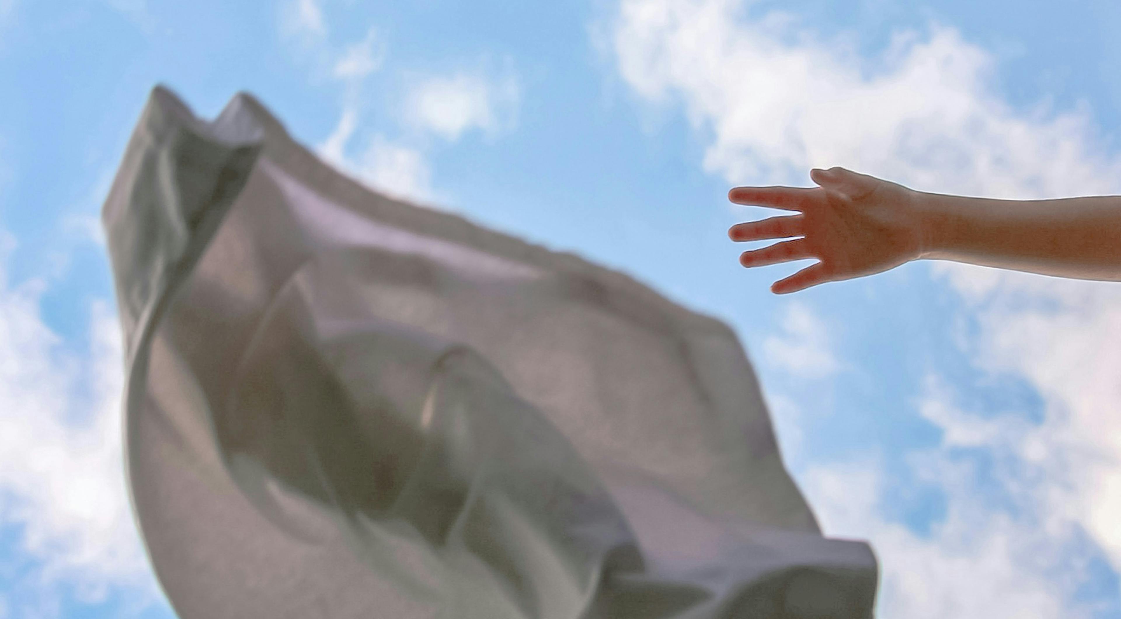 mano che lancia tessuto bianco in aria