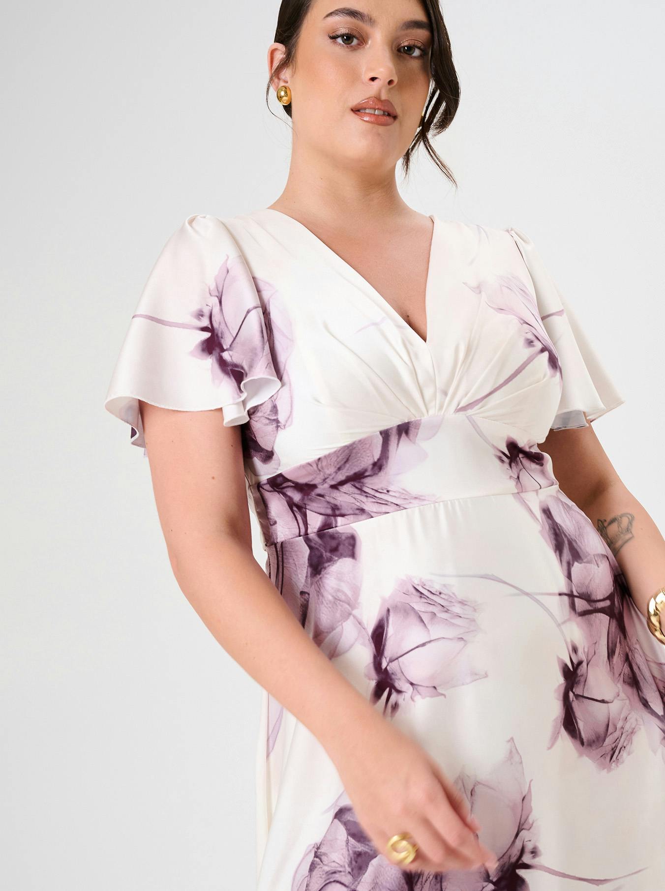 Curvy Woman in a floral dress with light purple flowers on white.