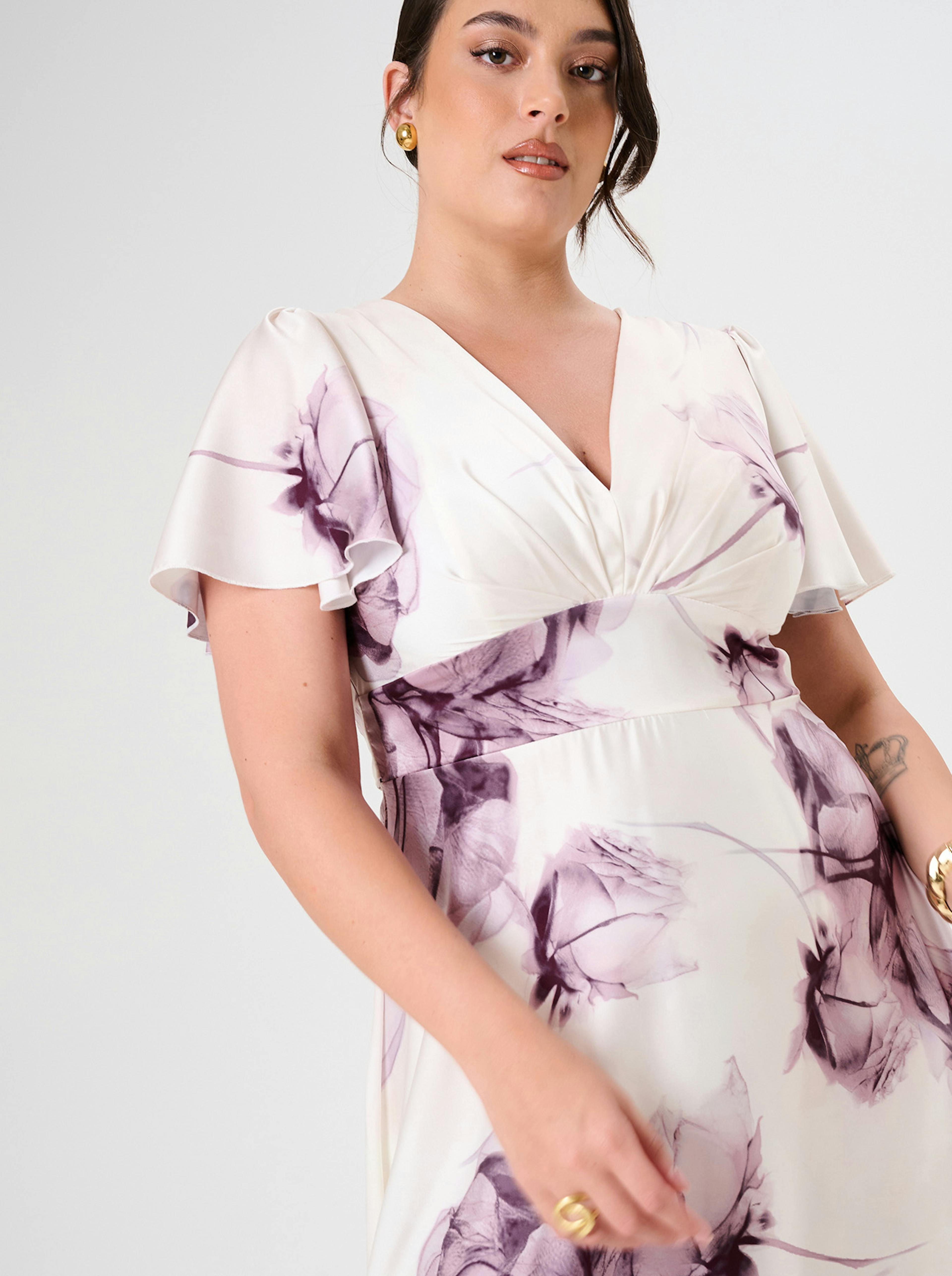 Curvy Woman in a floral dress with light purple flowers on white.