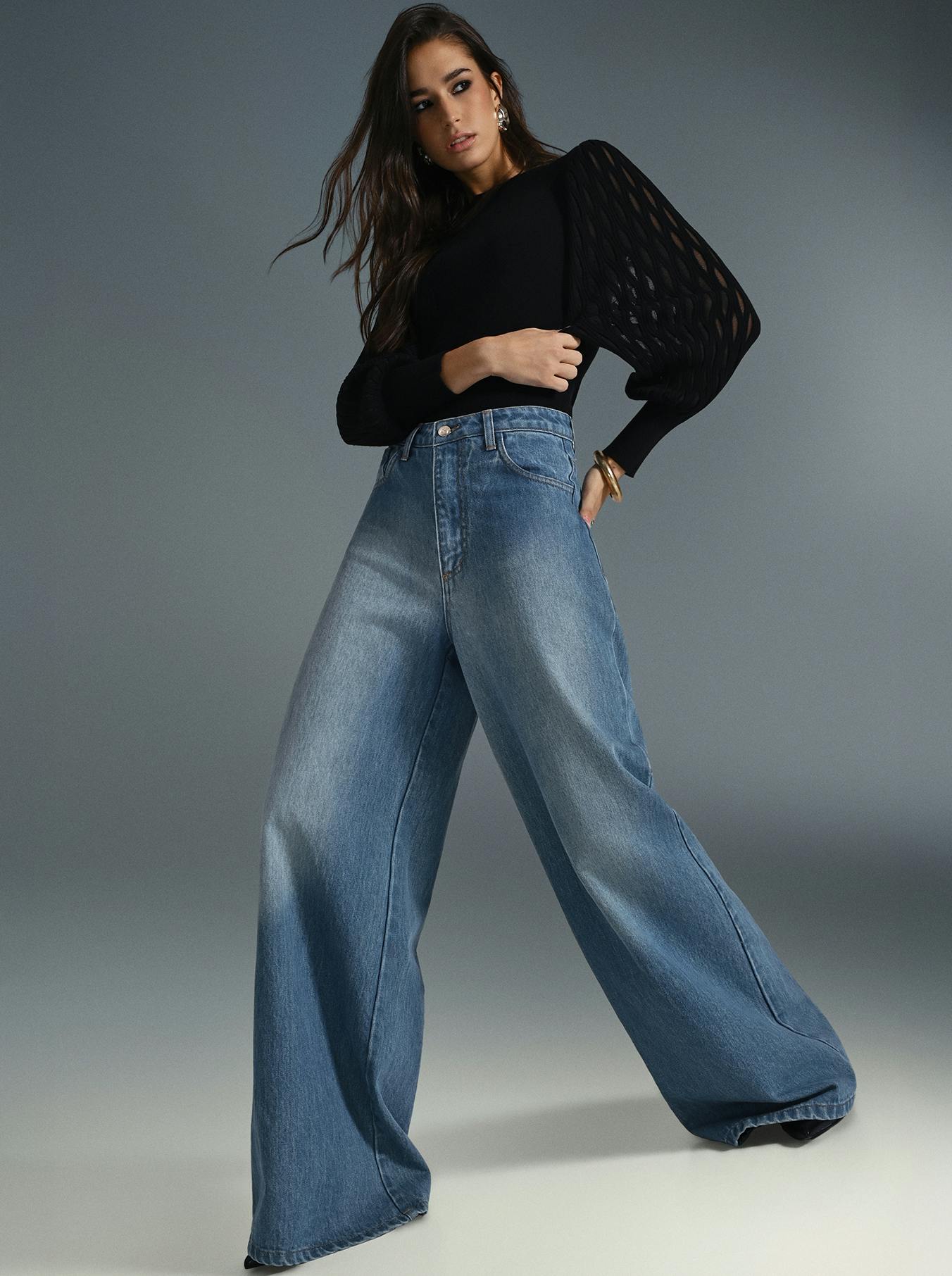 A model is dressed in wide leg jeans made of denim and a black top, presenting a trendy and casual fashion look.