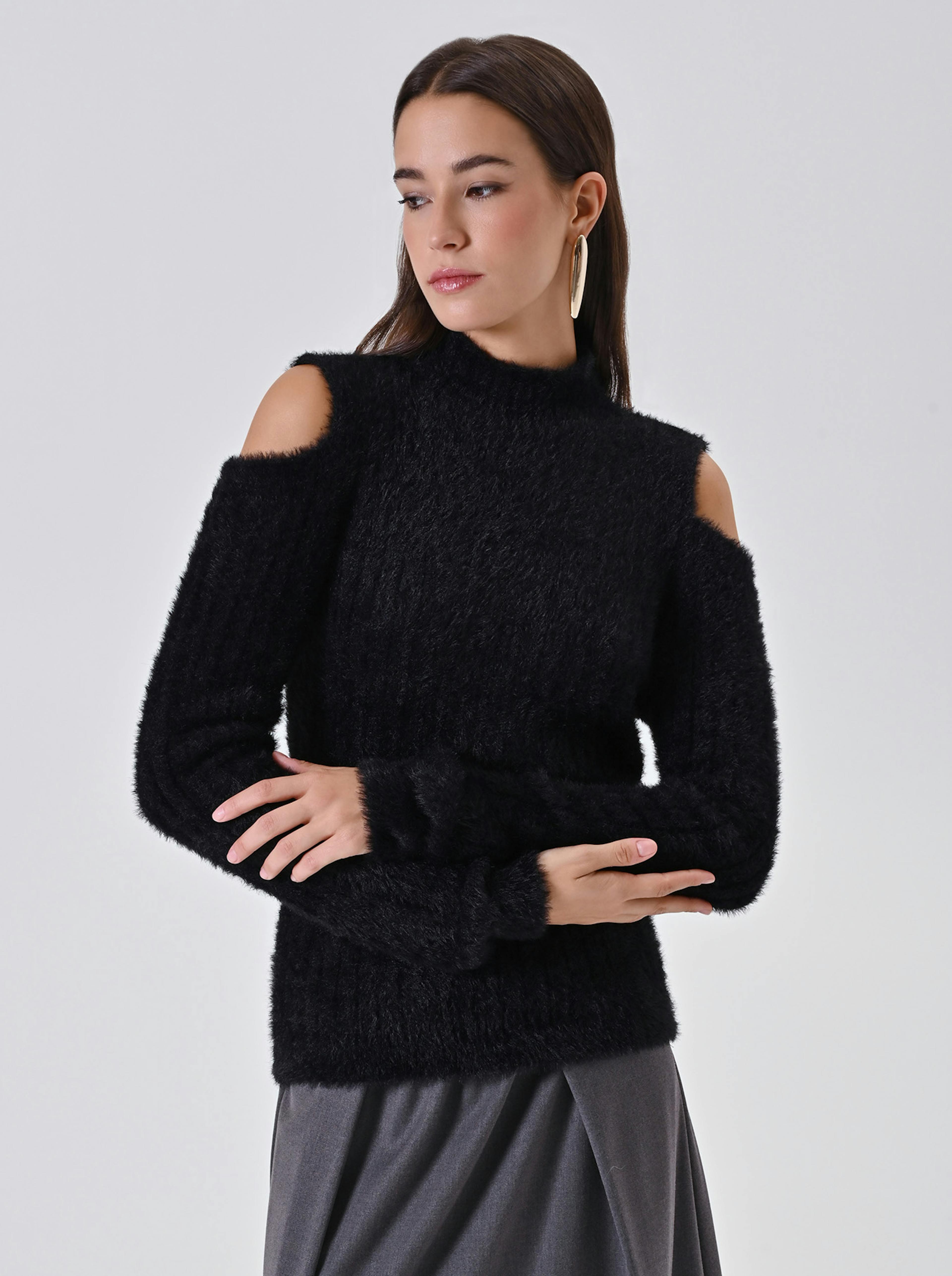 A woman in a stylish black fuzzy sweater with exposed shoulders and a gray skirt gazes to the side, exuding a calm and confident vibe.