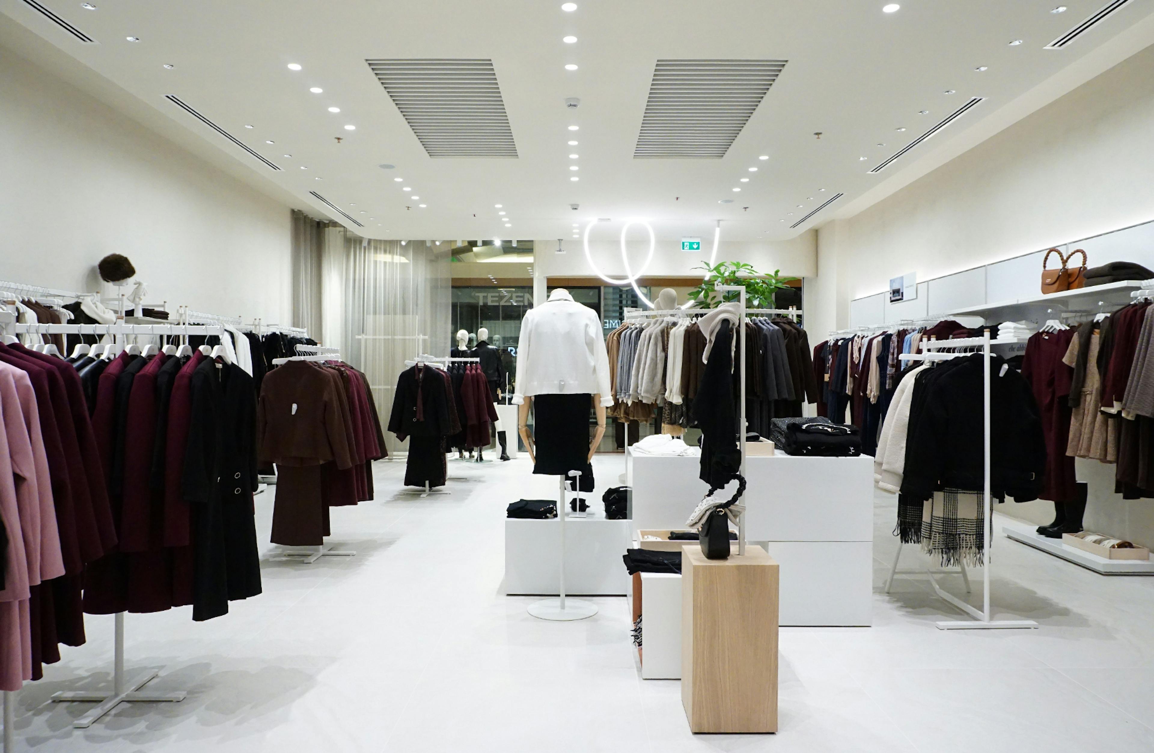 Bright modern clothing store with neatly arranged racks of stylish winter garments in shades of burgundy and beige, creating a chic atmosphere.