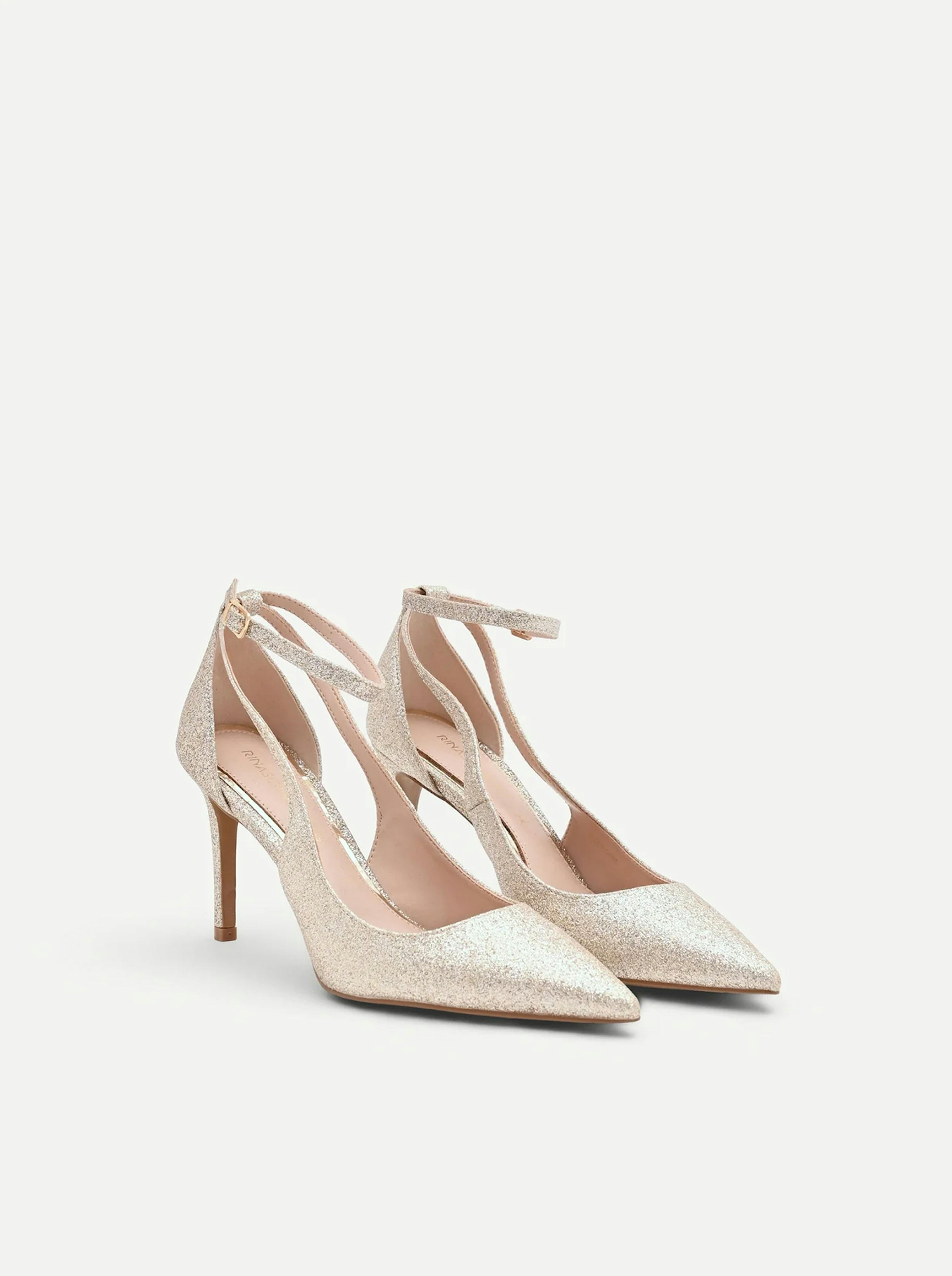 Champagne-colored glitter pumps with pointed toes, stiletto heels, and ankle straps on a white background.