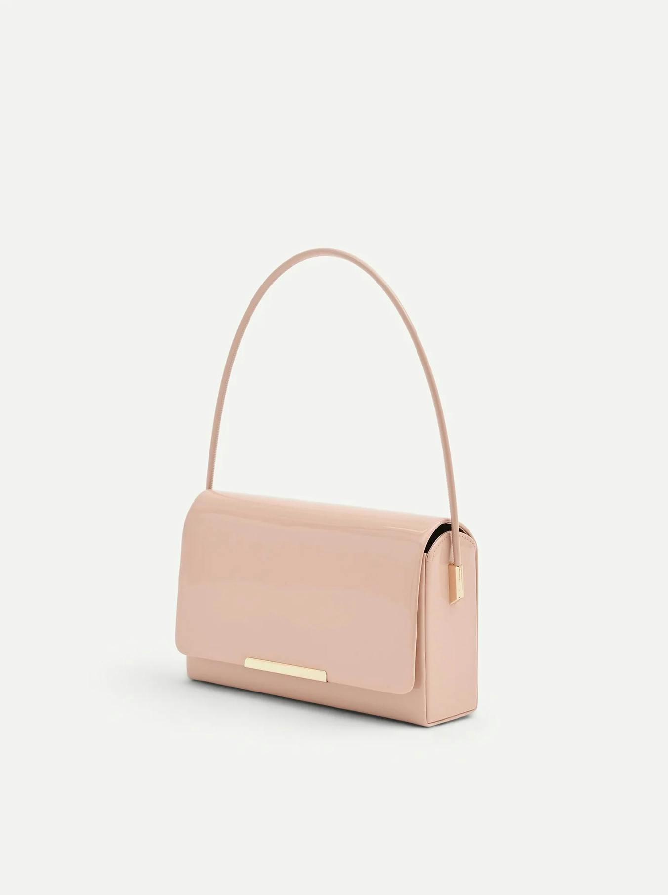 Elegant blush pink patent leather shoulder bag with a slim strap and minimalist rectangular design. Features a gold-toned metal bar closure, perfect as a chic evening baguette bag or wedding guest accessory.