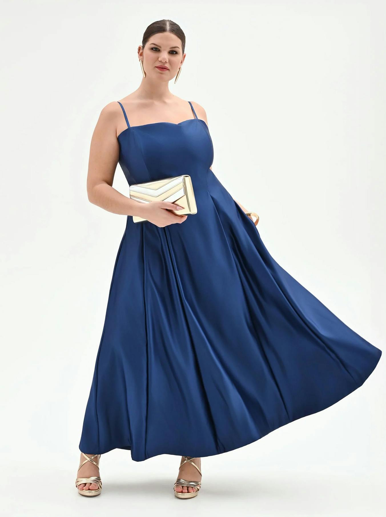 Stunning royal blue satin maxi dress featuring delicate spaghetti straps and a flowing pleated skirt. A vibrant and elegant choice for bridesmaids or summer evening events, paired with gold strappy sandals and a metallic clutch.