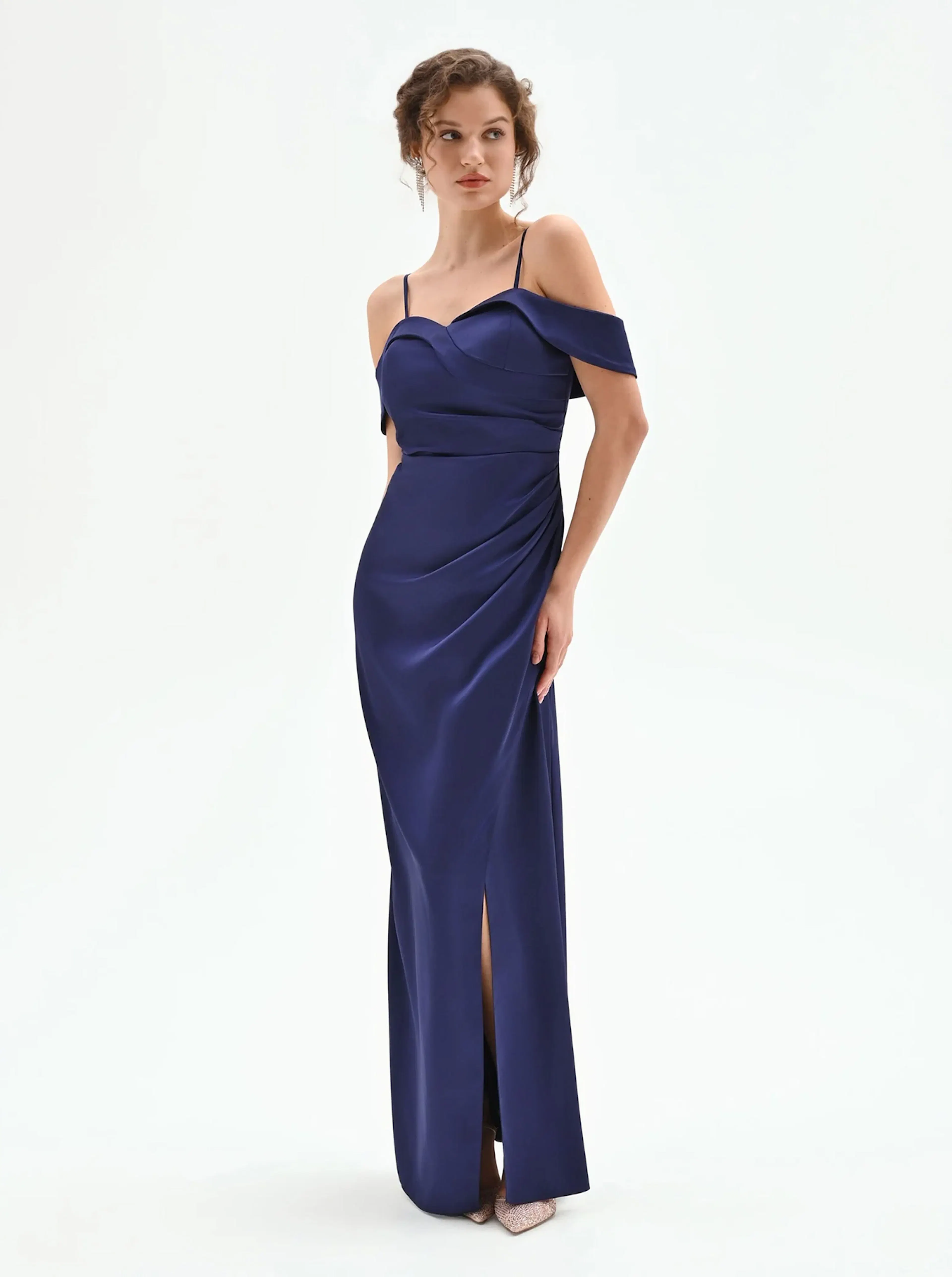 A woman models a fitted navy blue evening gown with a sweetheart neckline, off-the-shoulder sleeves, and a thigh-high slit.