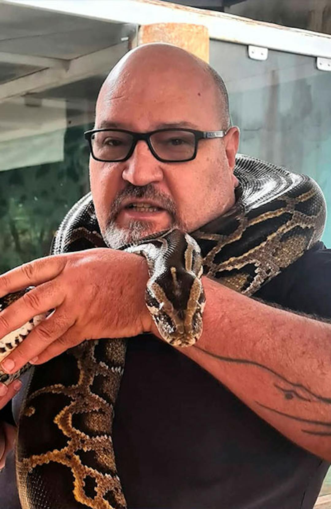 Homem exibindo uma espécie de serpente enrolada em seu pescoço como um "selfie" amigável com o animal