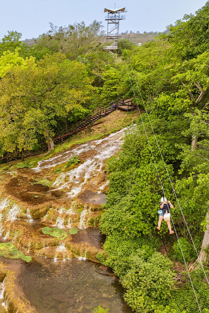 Paisagem natural com uma cachoeira de tufas calcárias e vegetação exuberante, ideal para quem busca contato com a natureza e momentos de tranquilidade ao ar livre.