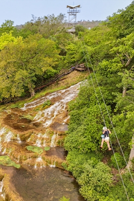 Paisagem natural com uma cachoeira de tufas calcárias e vegetação exuberante, ideal para quem busca contato com a natureza e momentos de tranquilidade ao ar livre.