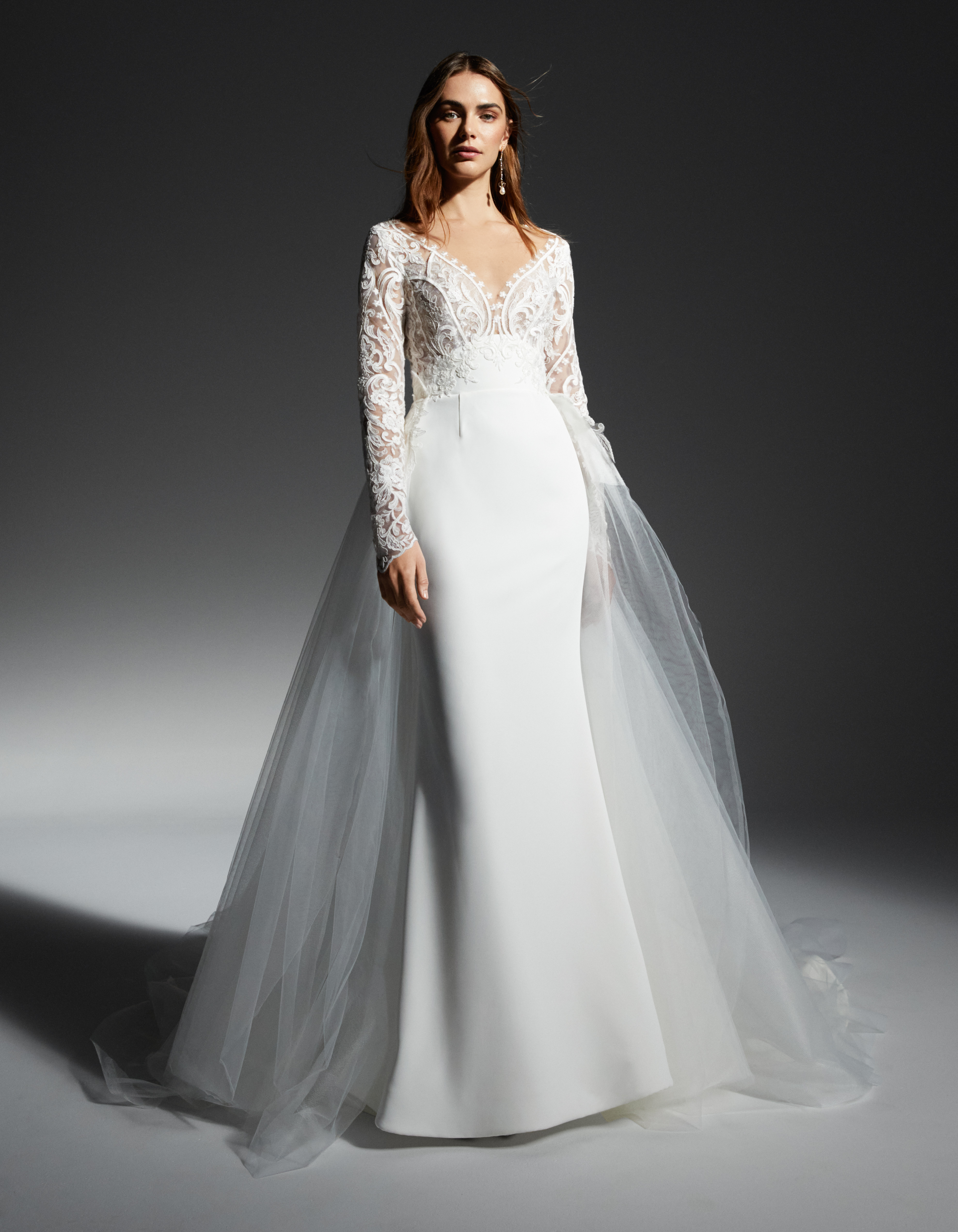 Kinsley long sleeve embroidered lace sheath gown with detachable tulle overskirt train, shown from the front.