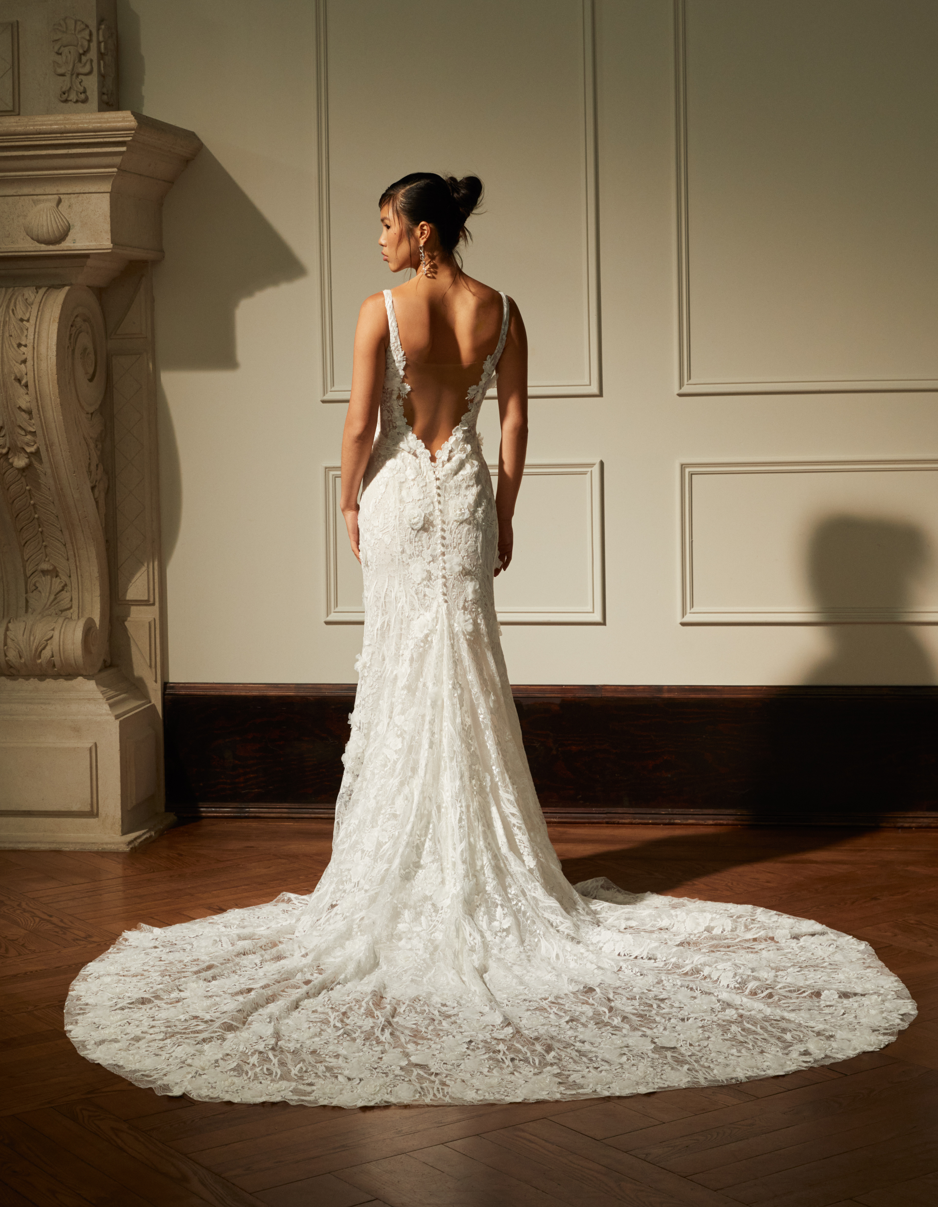 Bride wearing the Emberly gown from the back, showing the open back, pearl buttons, and full floral train.