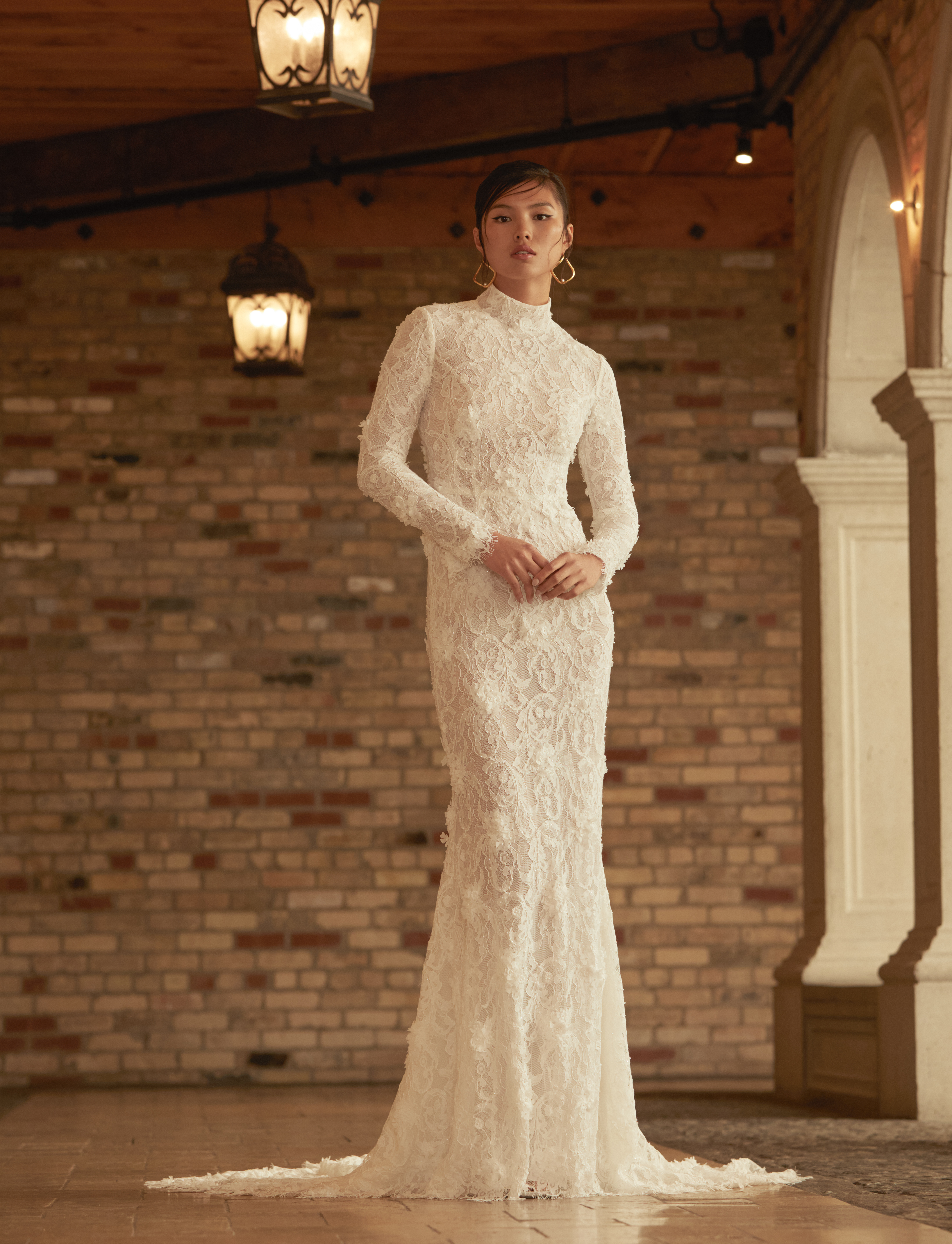Bride wearing the Heidi long-sleeve lace sheath gown with mock neckline and soft train.