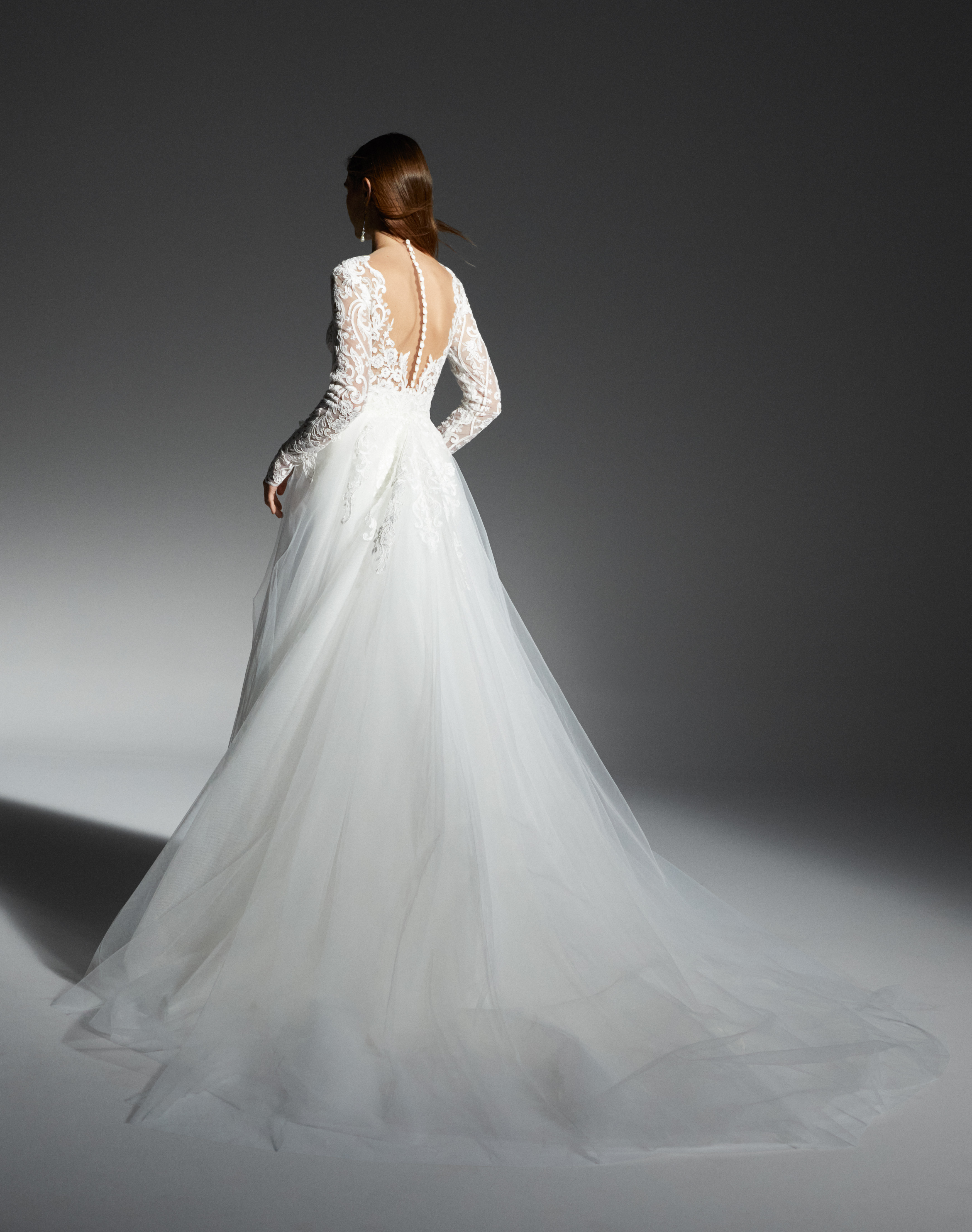 Back view of Kinsley long sleeve lace sheath gown with detachable tulle overskirt train.