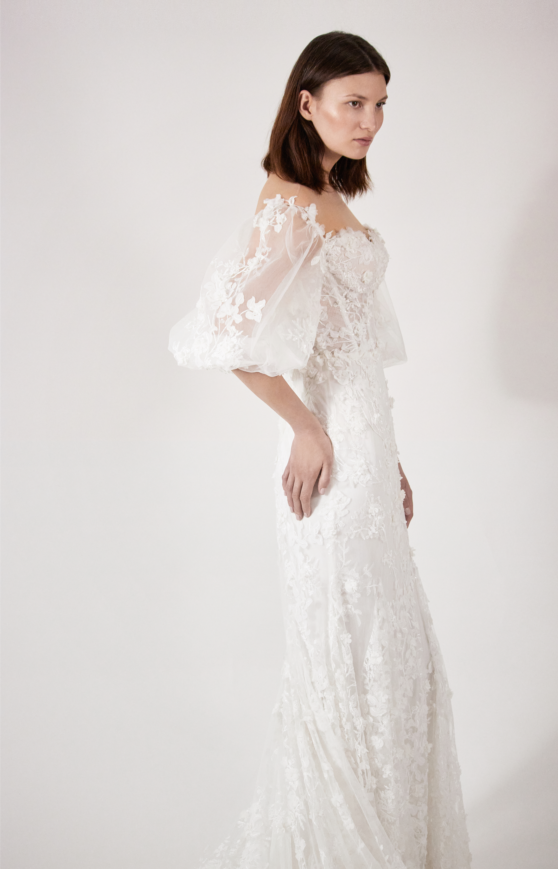Side view of the Neva gown, showing the portrait neckline, fitted lace sheath silhouette, and balloon sleeve.
