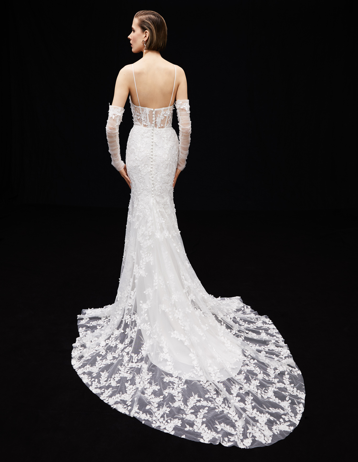 Back view of Dakota sheath gown with 3D floral lace, hand-applied embroidered lace, and ruched tulle sleeves.
