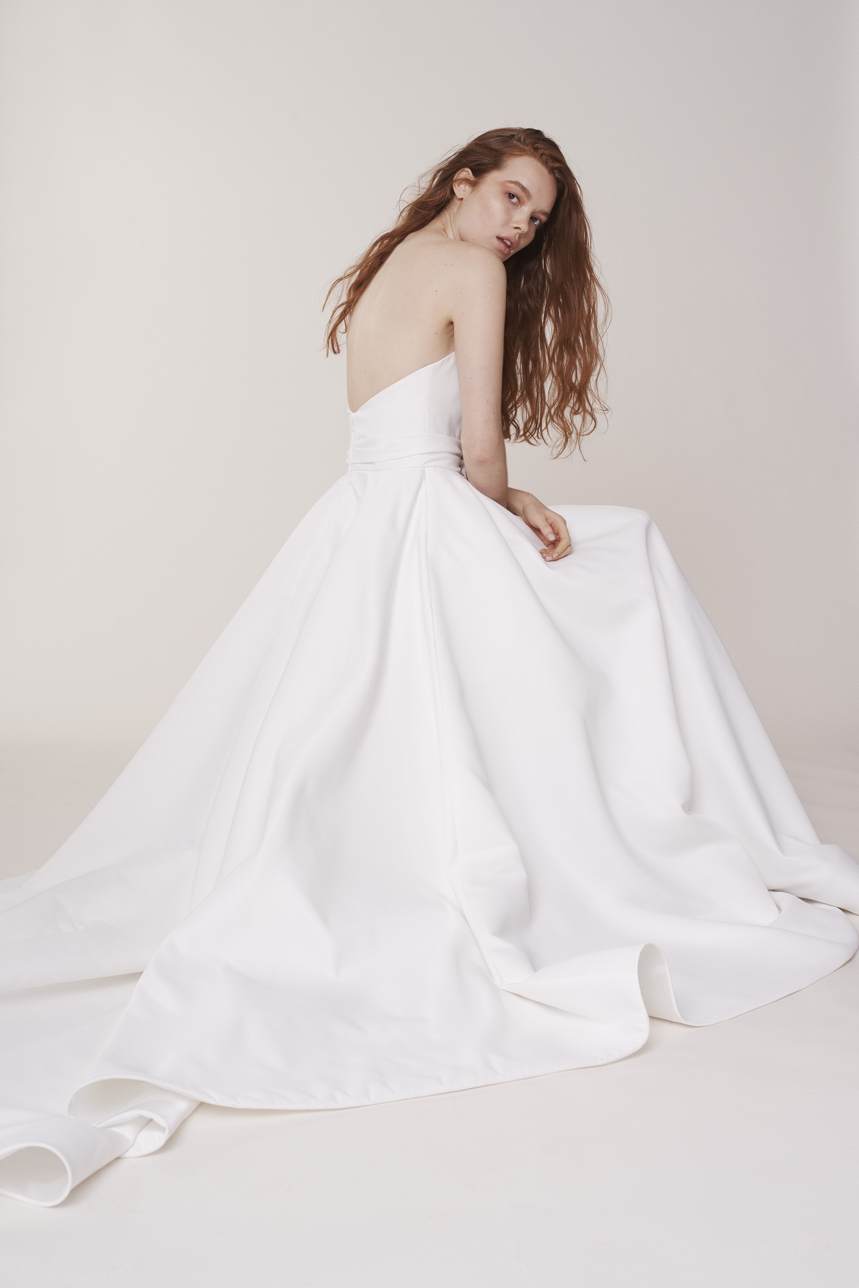 Ashford ivory matte satin ball gown with draped sweetheart bodice and full skirt, shown seated.