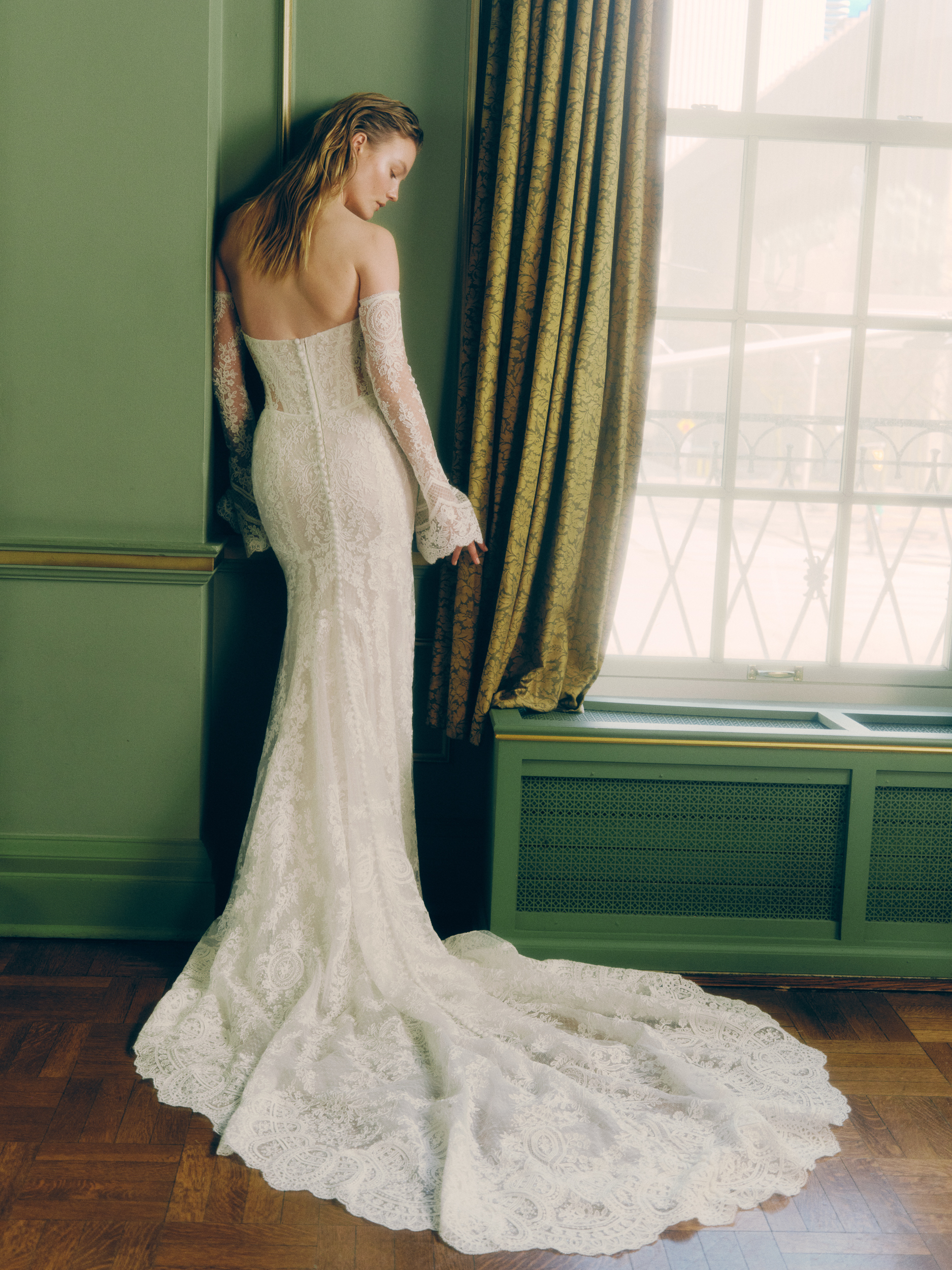 Side view of the Viv gown, showing the fitted lace silhouette, sheer corset detail, and elegant lace train.