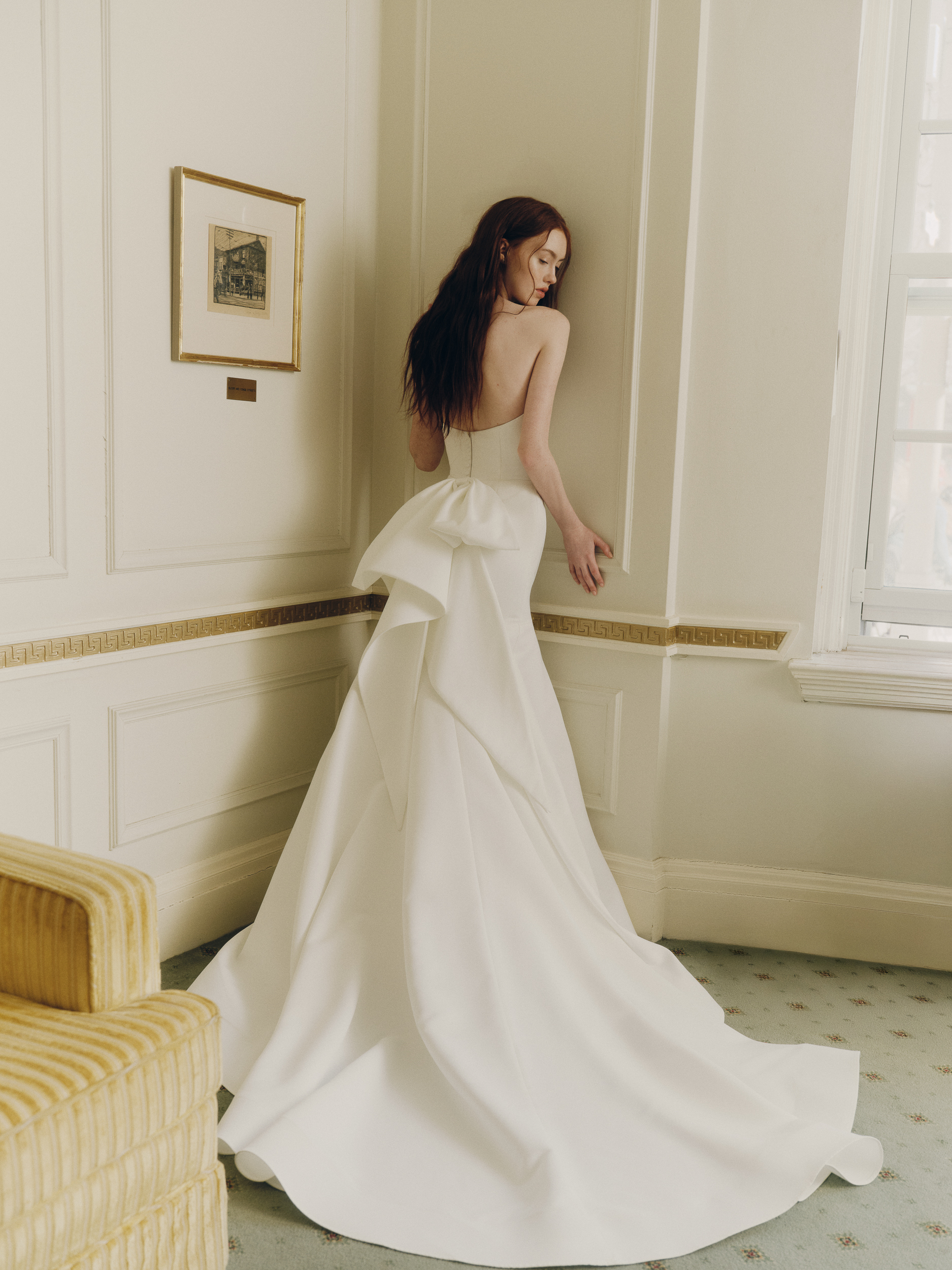 Bride wearing the Fenn gown from the side, showing the mermaid silhouette, soft train, and bow detail at the waist.