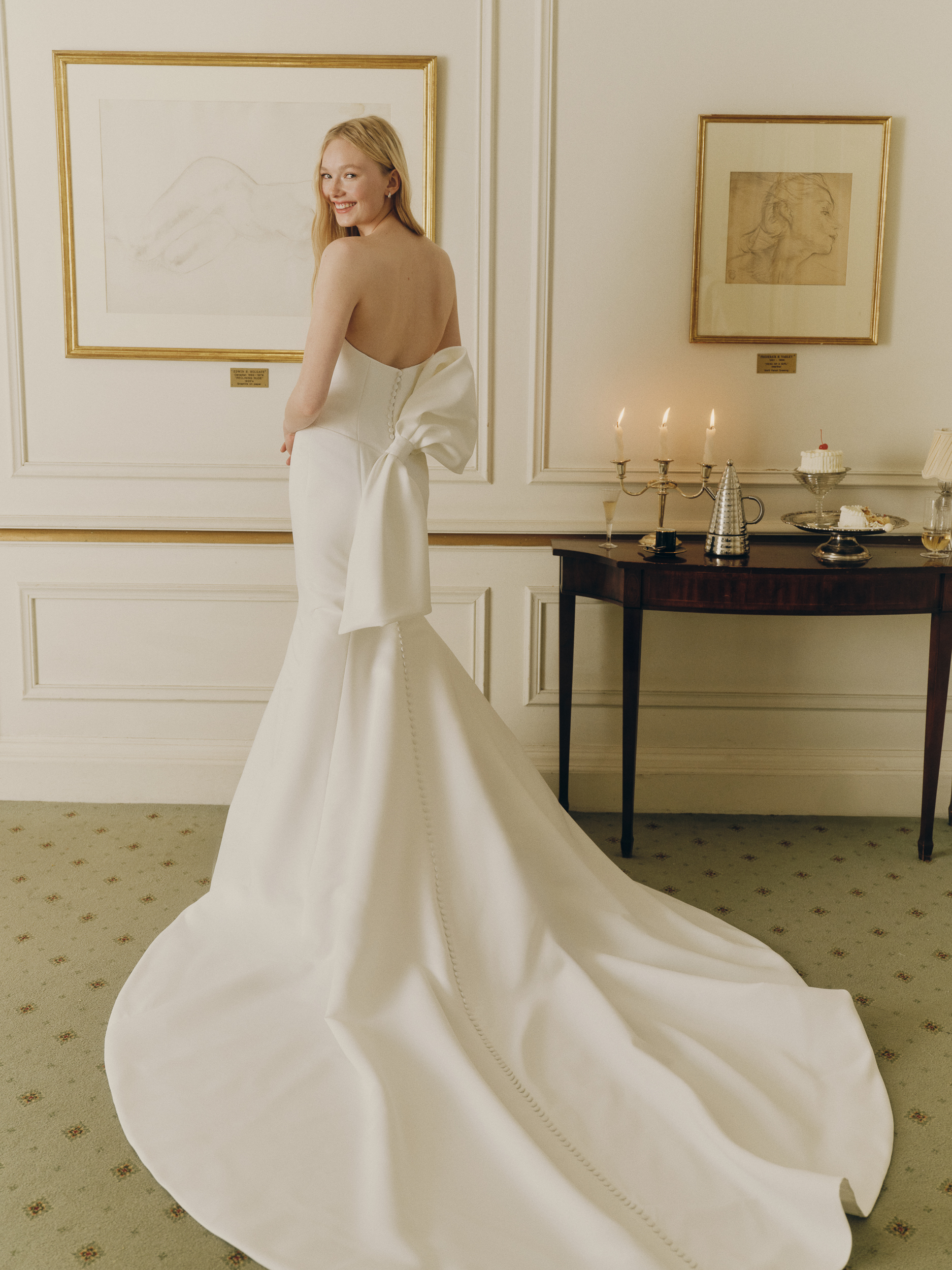 Full-length back view of the Norra gown, showing the plunging sweetheart neckline, fit-and-flare silhouette, and dramatic train.