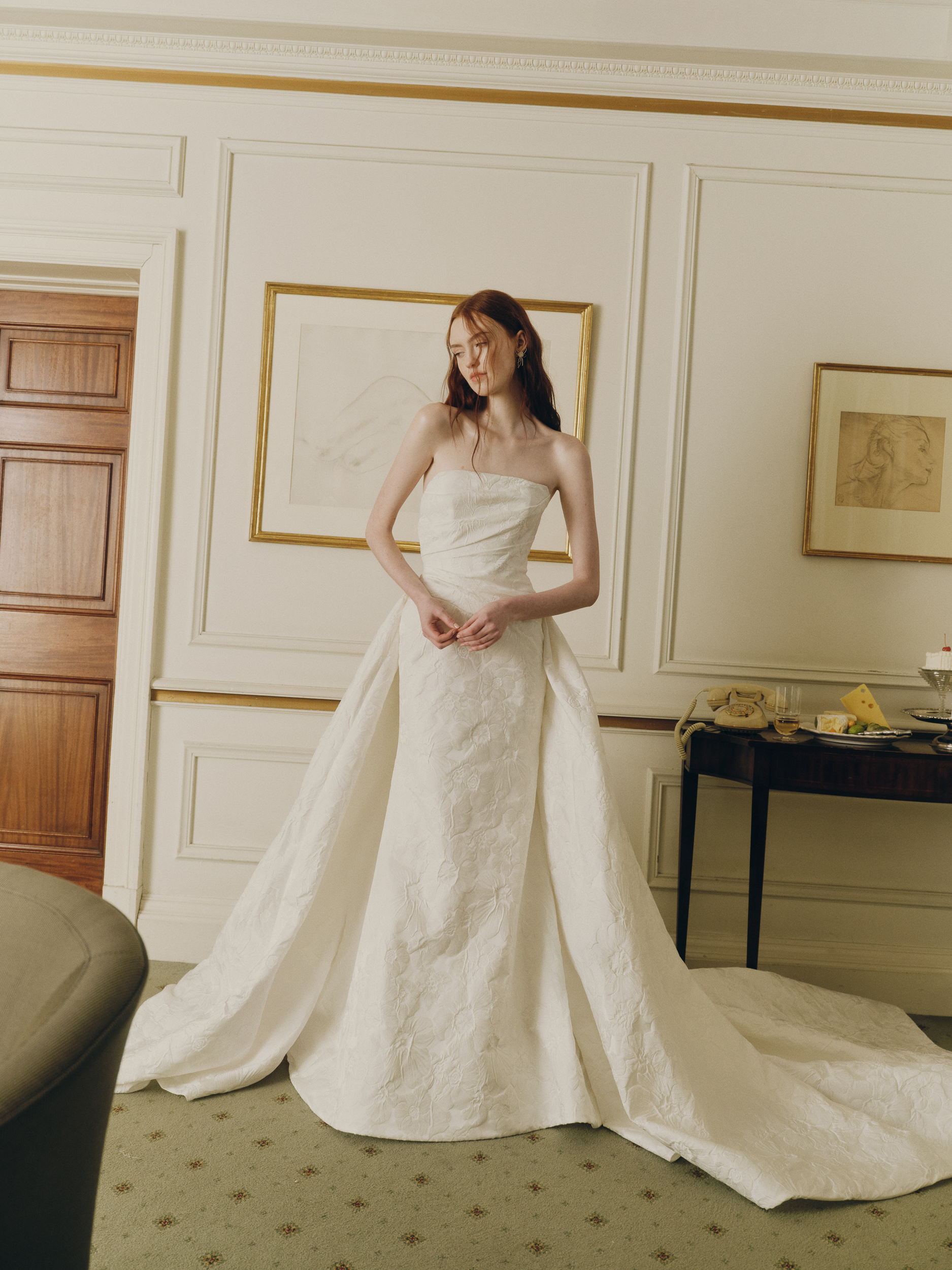 Bride wearing the Prie strapless gown, showing the draped bodice, basque waist, and full overskirt.