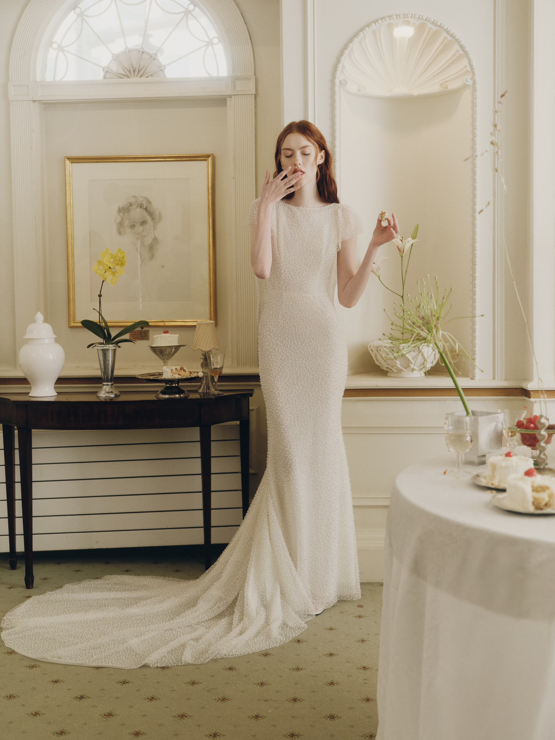 Bride wearing the Shia pearl-beaded sheath gown with flutter sleeves and soft train.