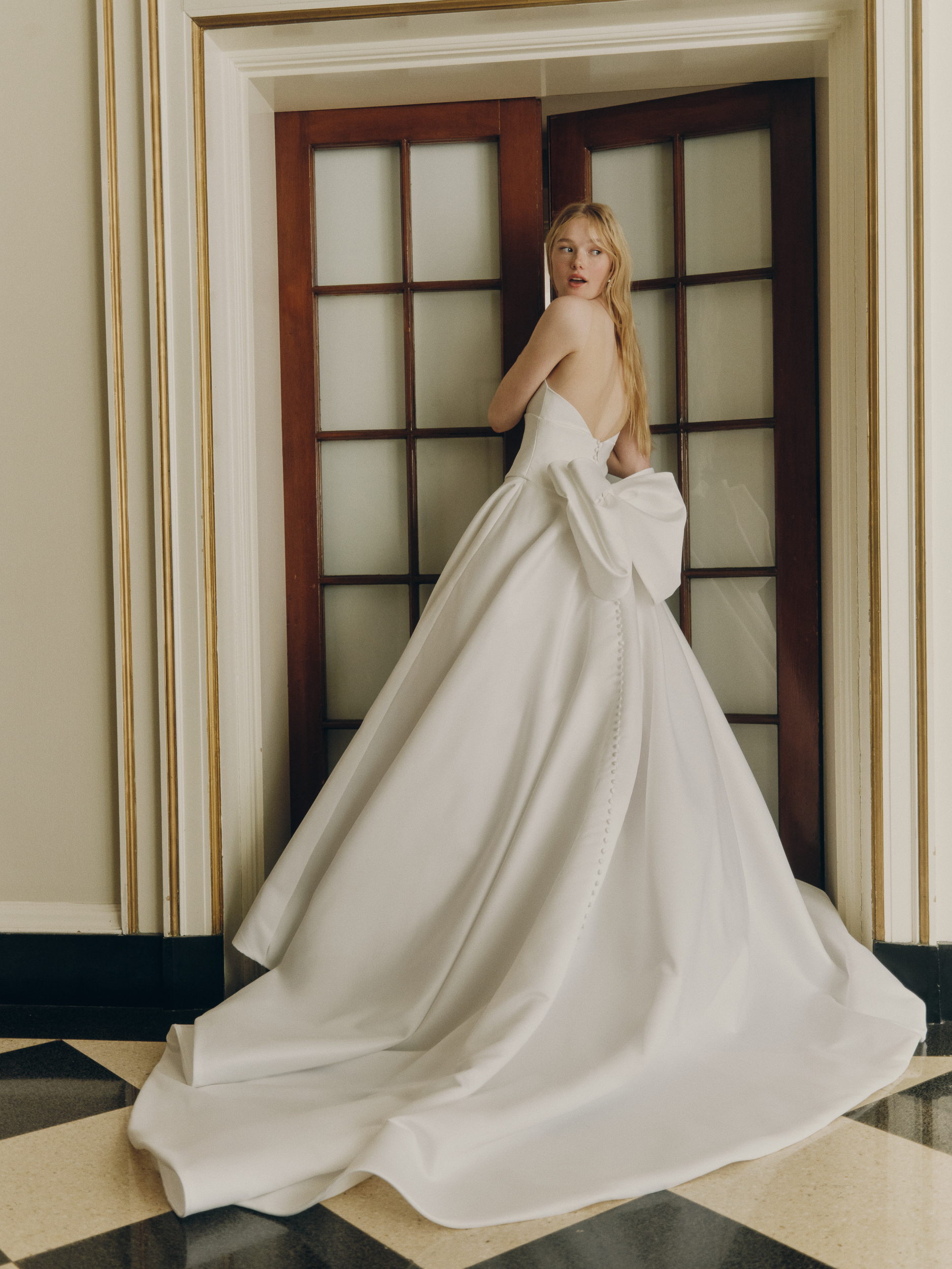 Bride wearing the Wynn ballgown from the side, showing the draped corset bodice, full skirt, and train.