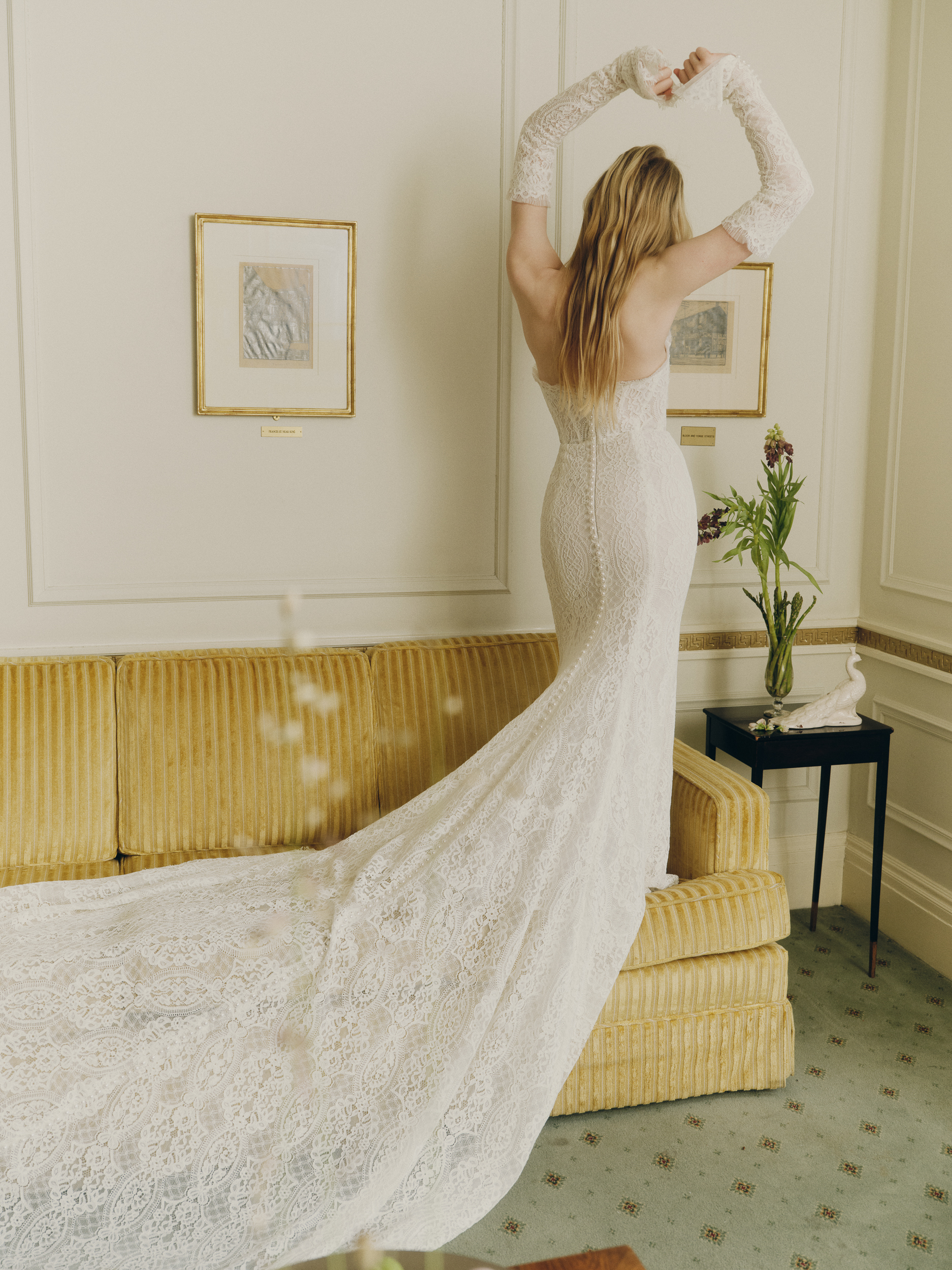 Bride wearing the Emme sheath gown with translucent lace bodice, lace opera cuffs, and soft train.