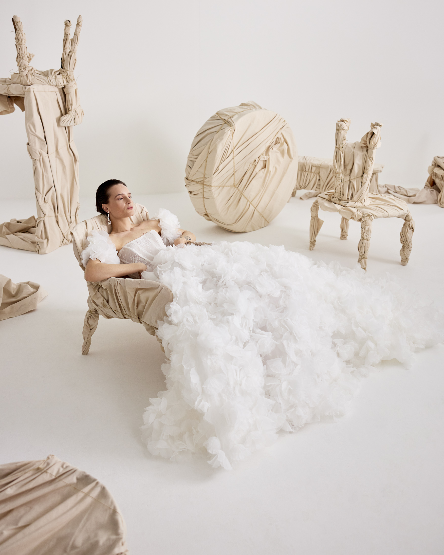 Bowie voluminous ball gown with 3D organza flowers over lace and detachable floral sleeves, shown seated.