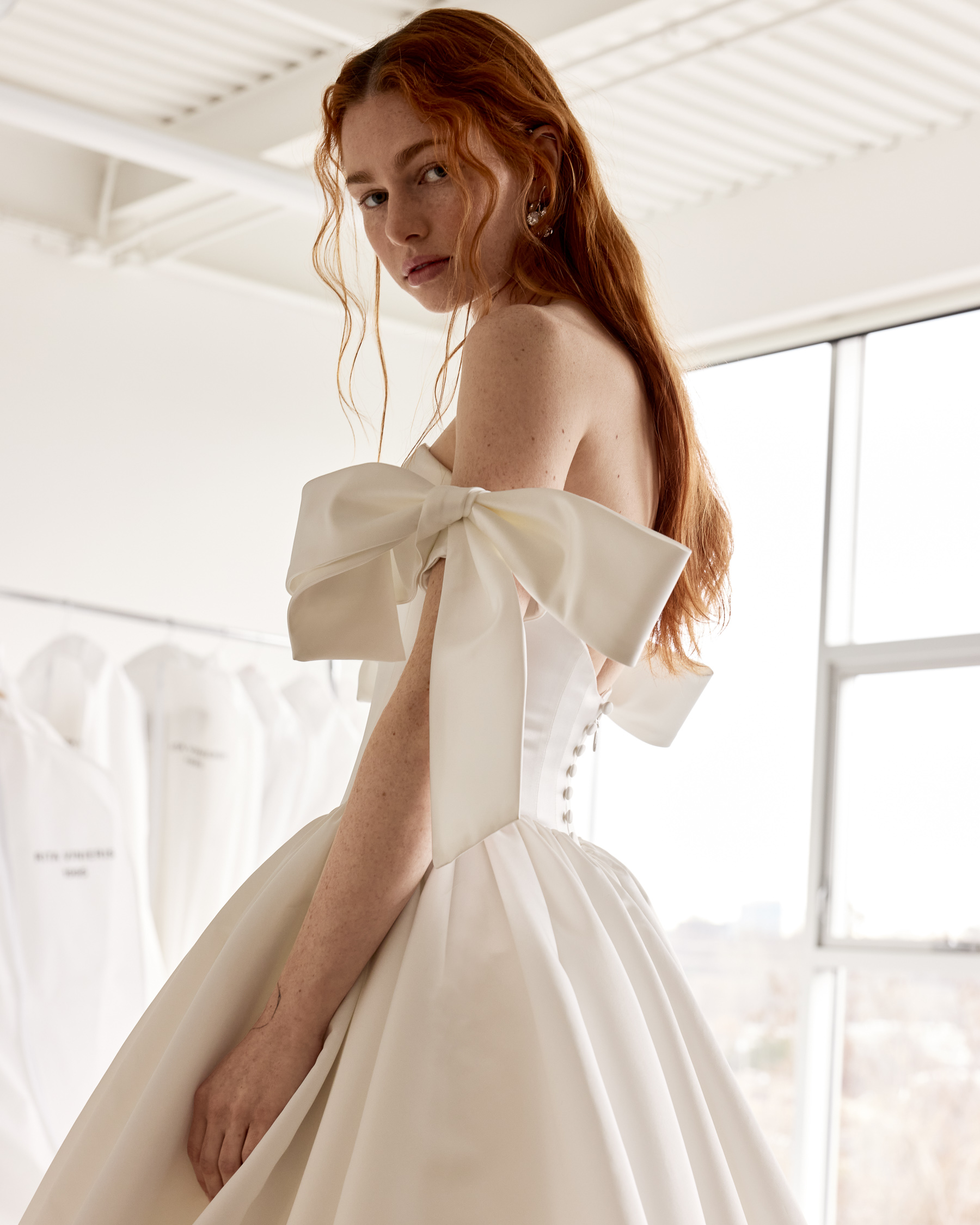 Side view of Danni satin ball gown with plunging neckline, full skirt, and detachable bow sleeve detail.