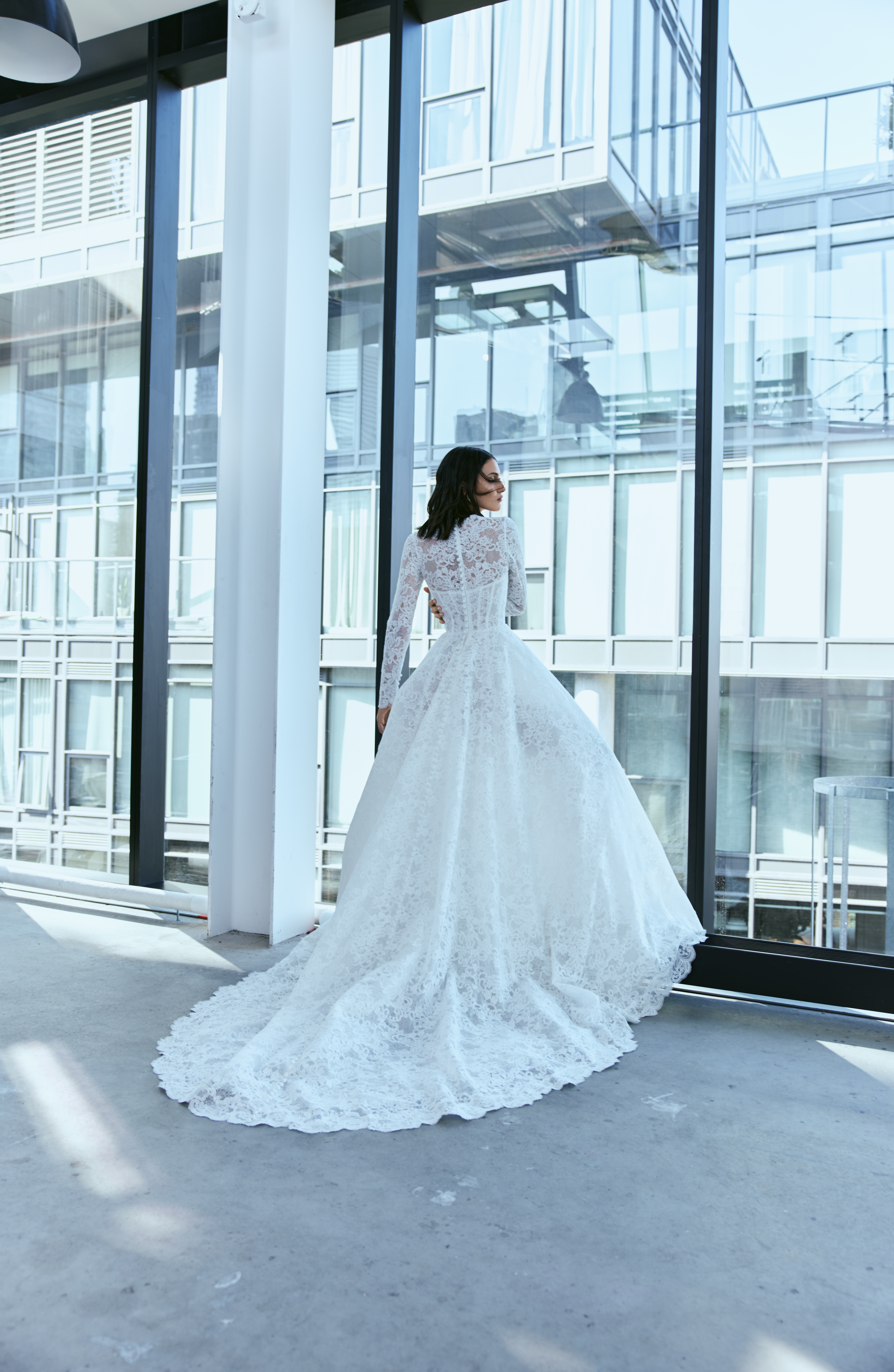 Bride wearing the Aspen ballgown from the back, showing the long lace sleeves and full train.