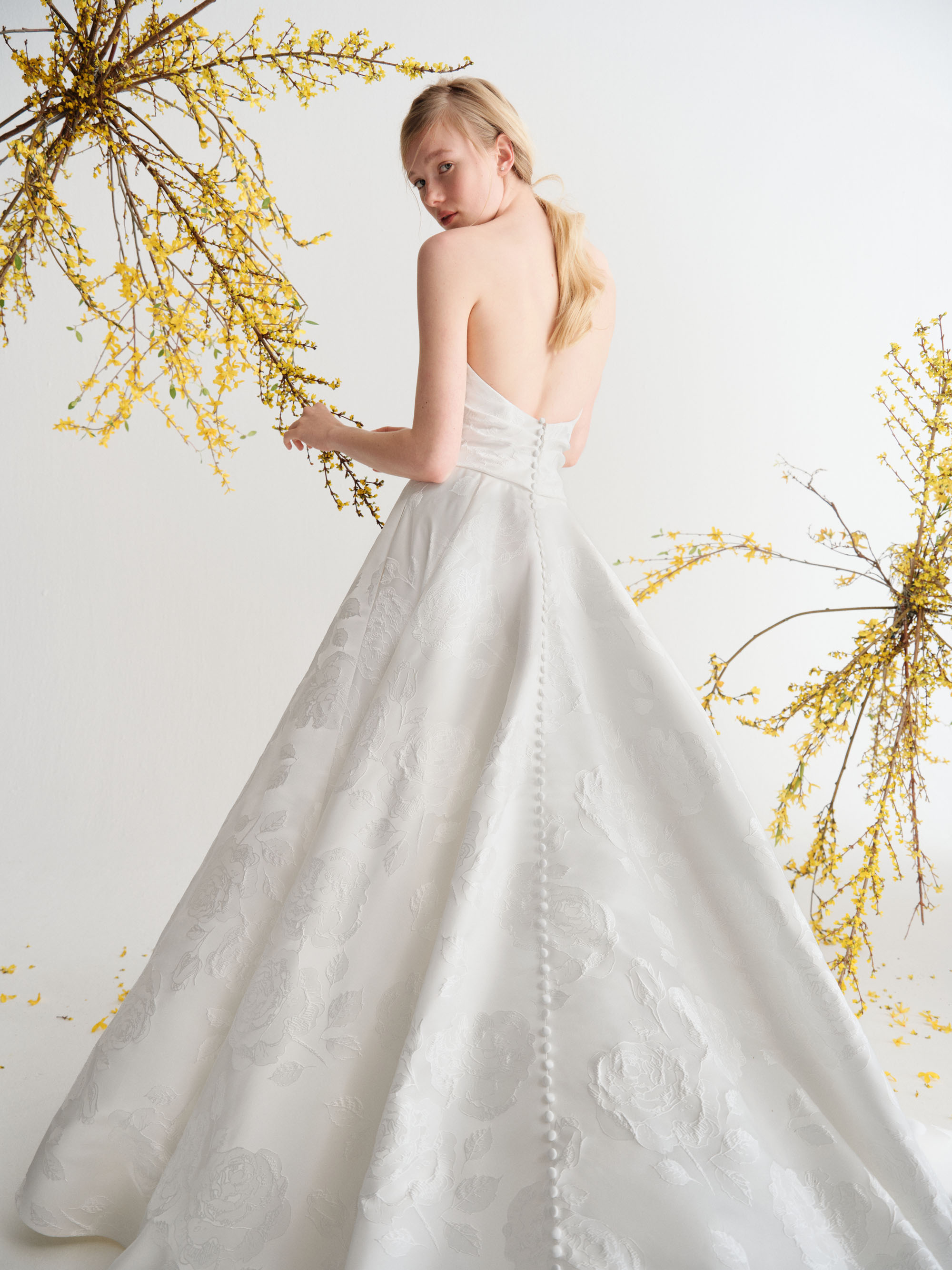 Back view of Leni showing the textured jacquard, full skirt, cathedral train, and jacquard-covered buttons.