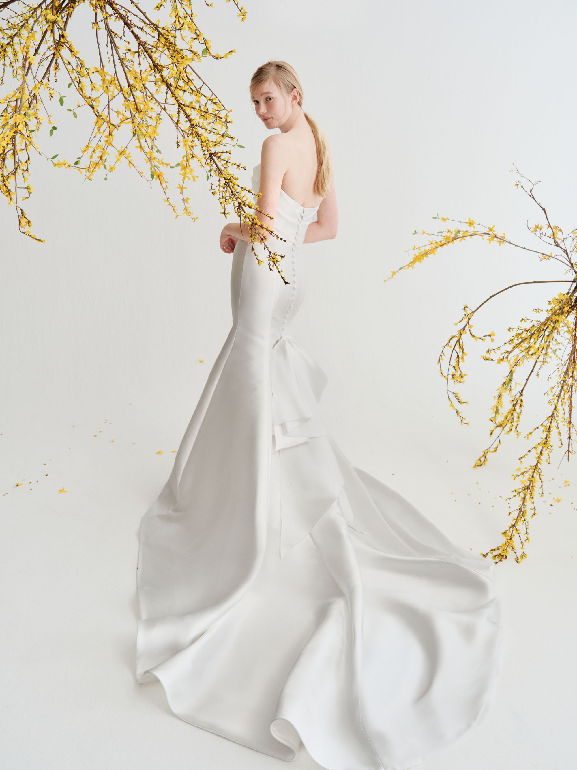 Full back view of Harlow showing the deconstructed bow, button detail, and dramatic flared skirt.