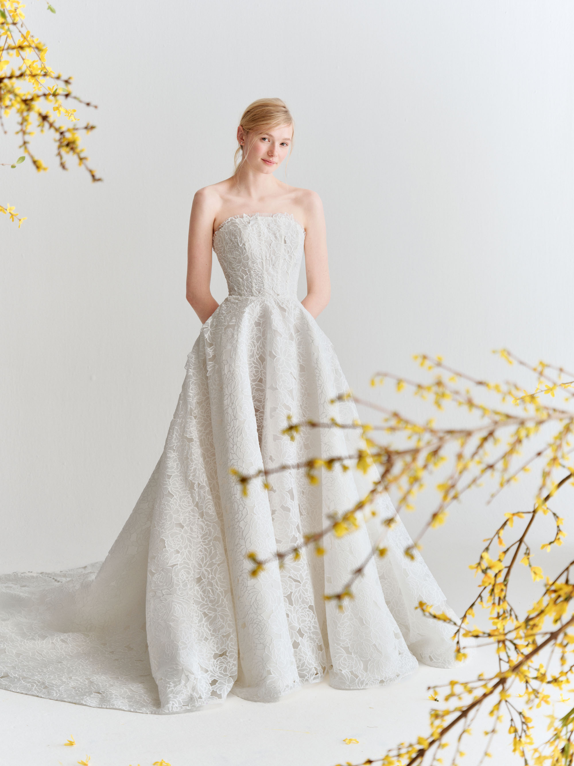 Full view of Sloane showing the strapless bodice, airy embroidered organza skirt, and satin buttons down the back.