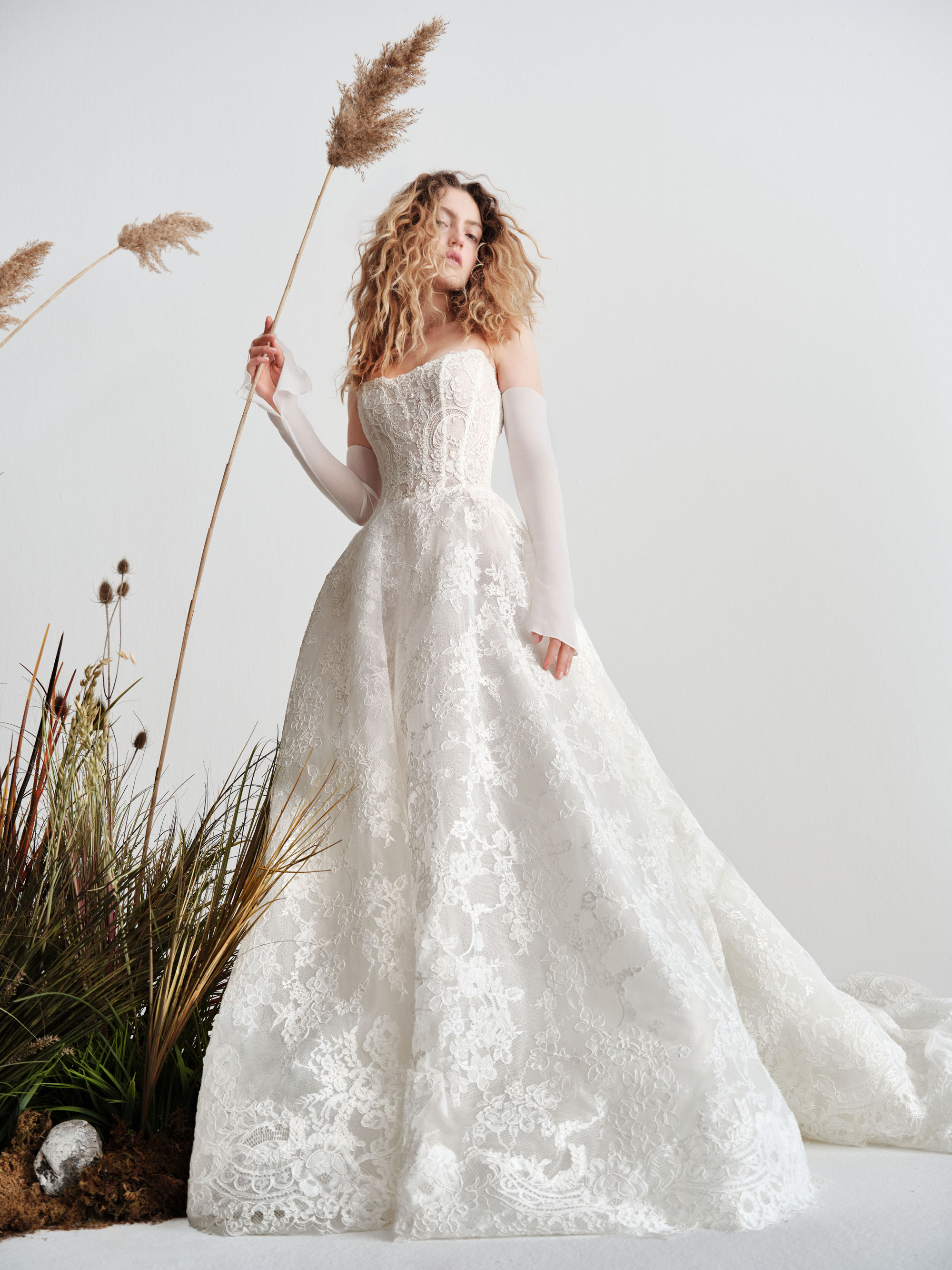 Reign Alyne SS27 corded Chantilly lace ball gown with a cat-eye boned bodice, low waist, and airy voluminous skirt, shown from the back.