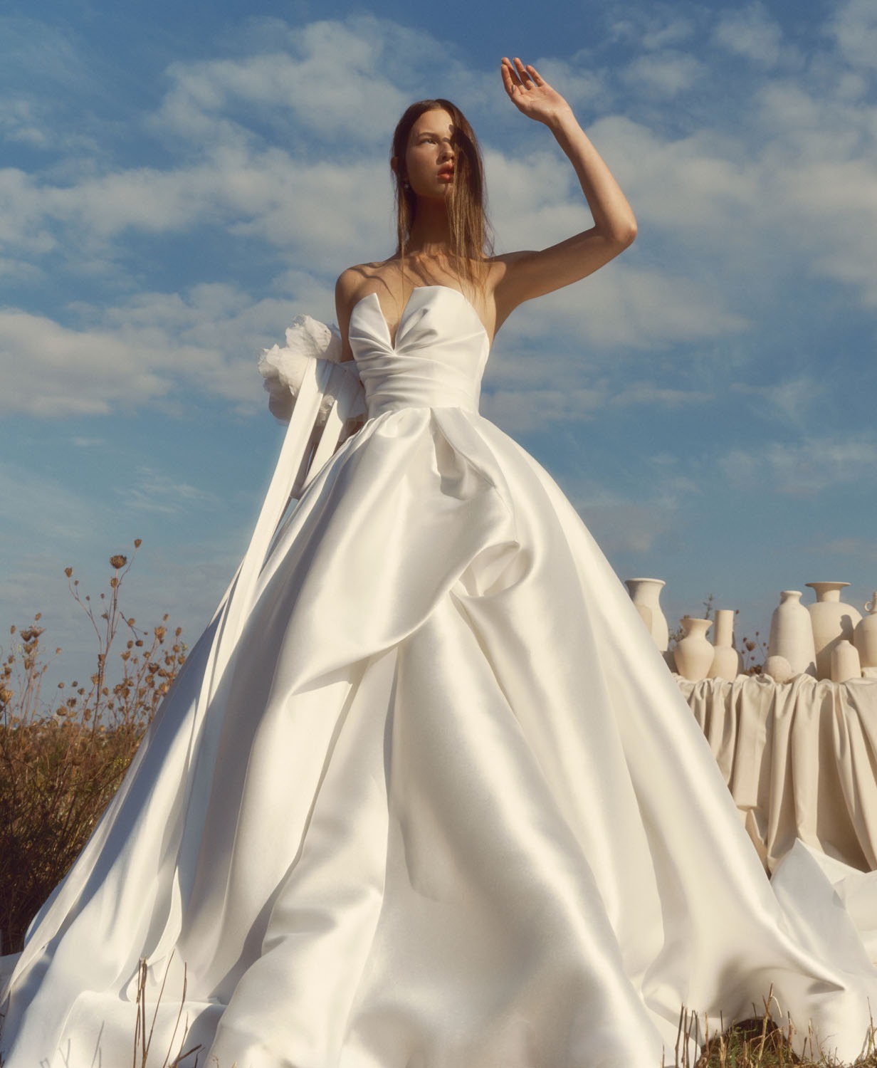 Glow Alyne FW26 silky strapless ball gown with sculpted sweetheart bodice, subtle V-front, and voluminous pleated skirt, shown from the front.