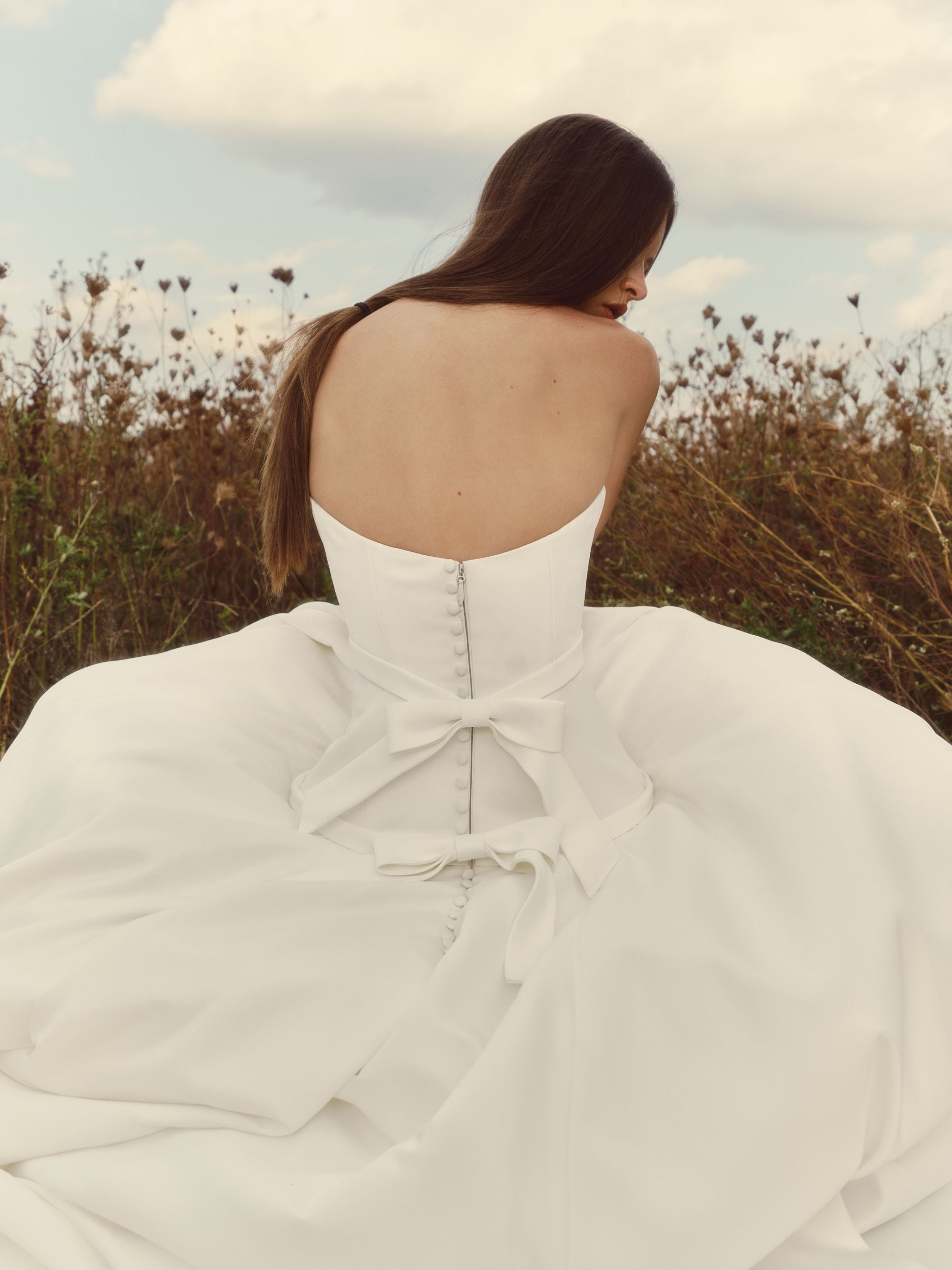 Back close-up of Pearl showing the low rounded back, delicate bow detail, and pearl buttons.