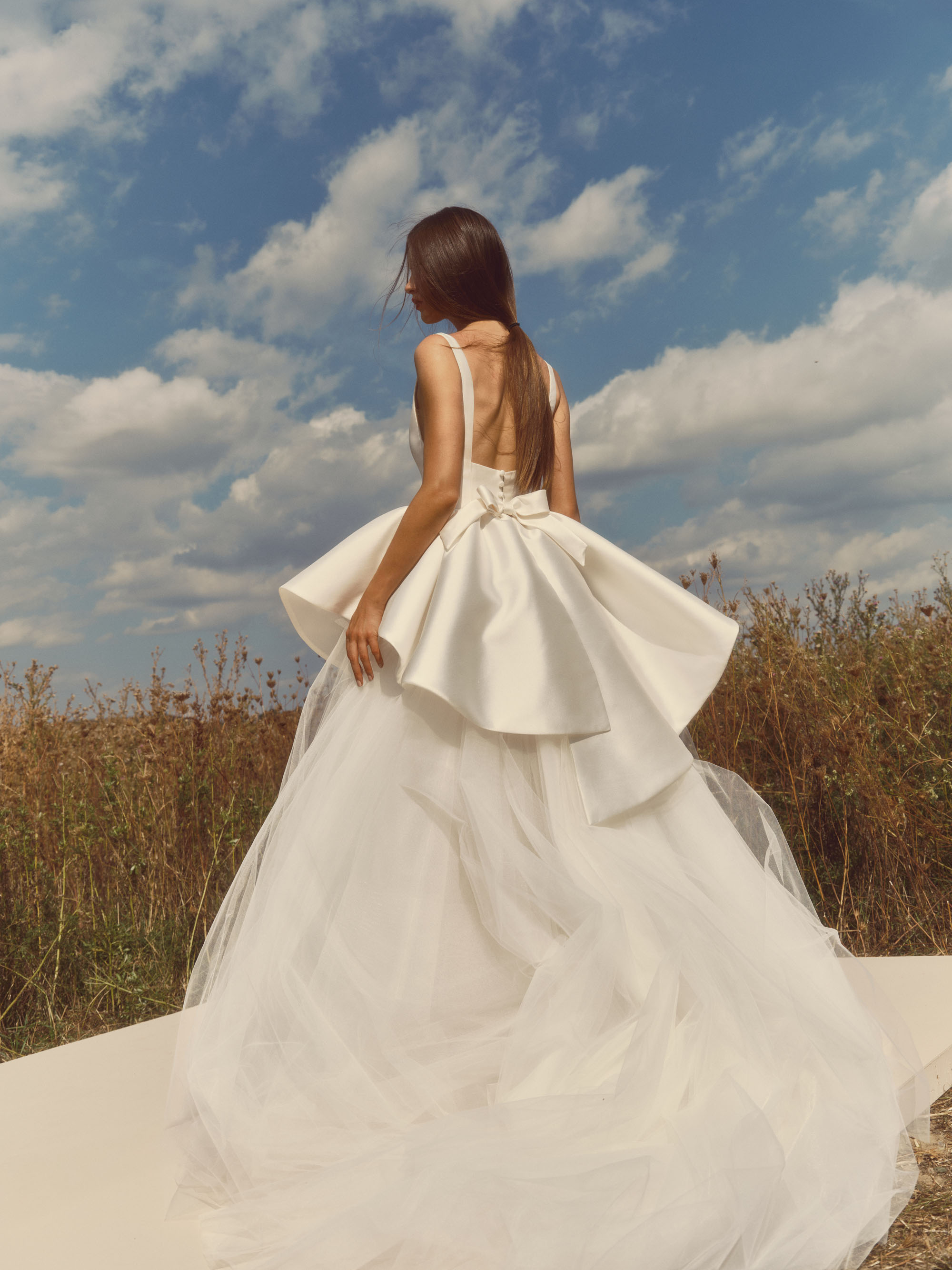 Back view of Ripple showing the layered peplum, wrapped waist bow, and voluminous tulle skirt.