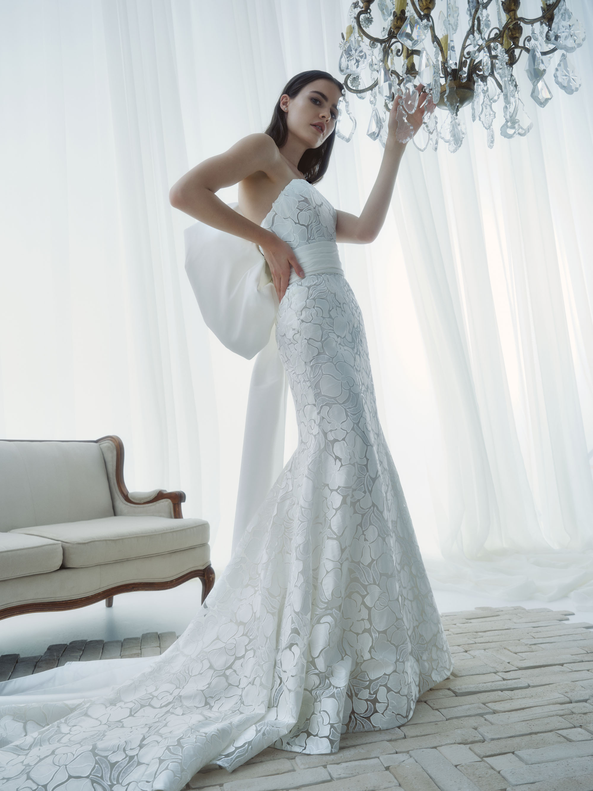 Essence RIVINI FW26 strapless fit-and-flare gown in beaded laser-cut lace with contrast taffeta cummerbund and sculpted bow, shown from the front.