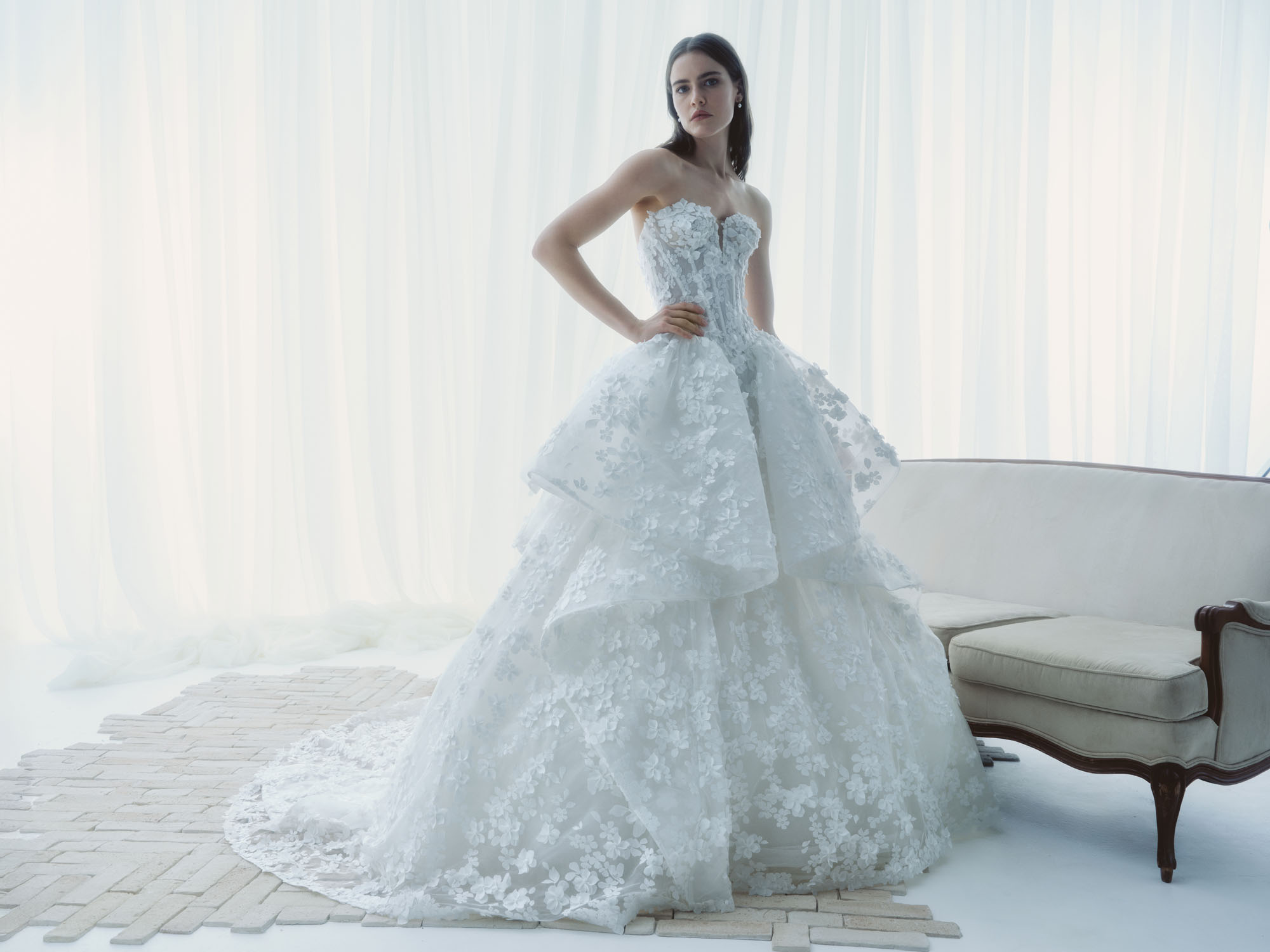 Full front view of Reverie showing the corseted bodice, airy peplum layers, and voluminous floral lace skirt.