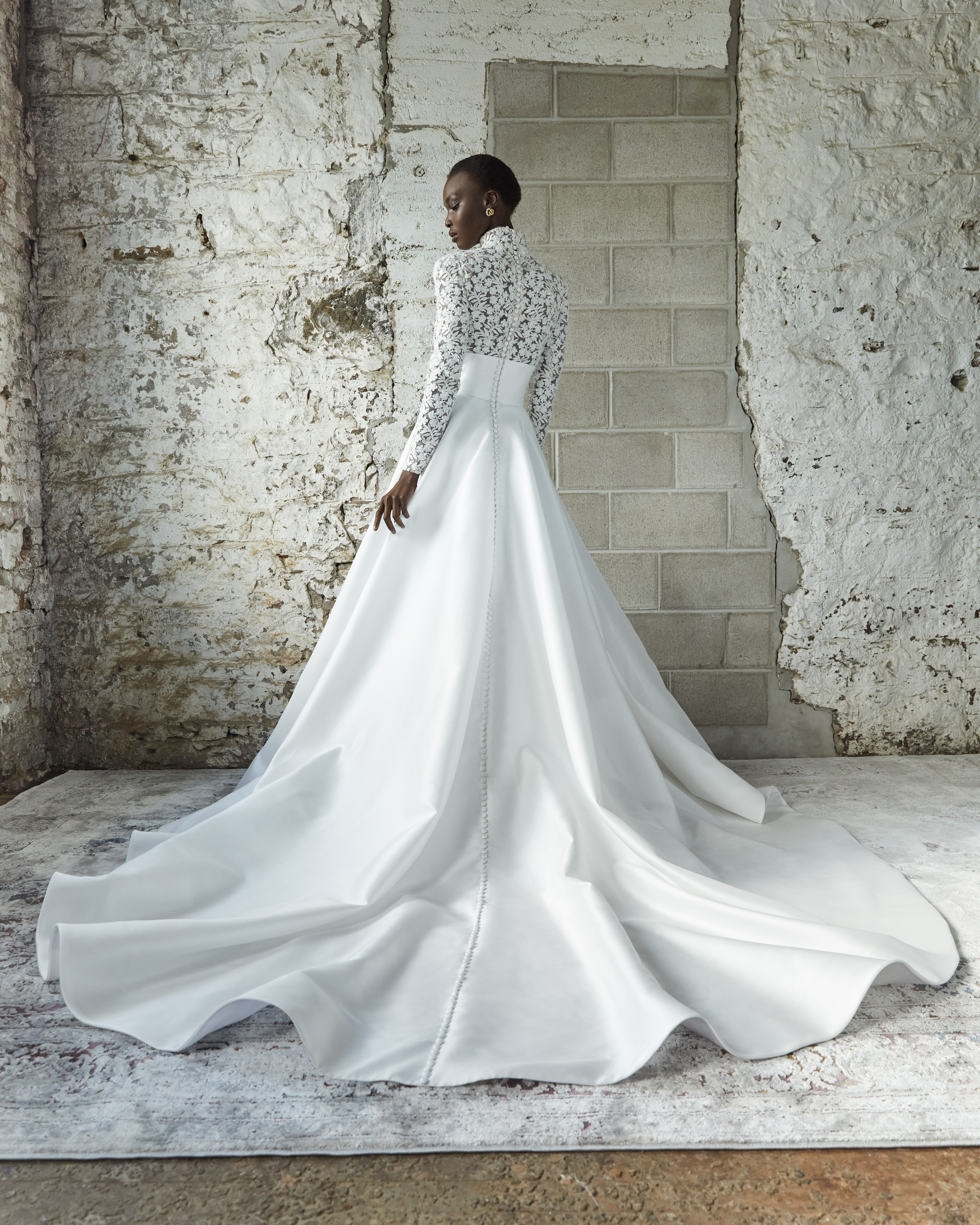 Bride wearing the Thyra grand ballgown from the back, showing the full skirt, mock neck, and sculpted puff sleeves.