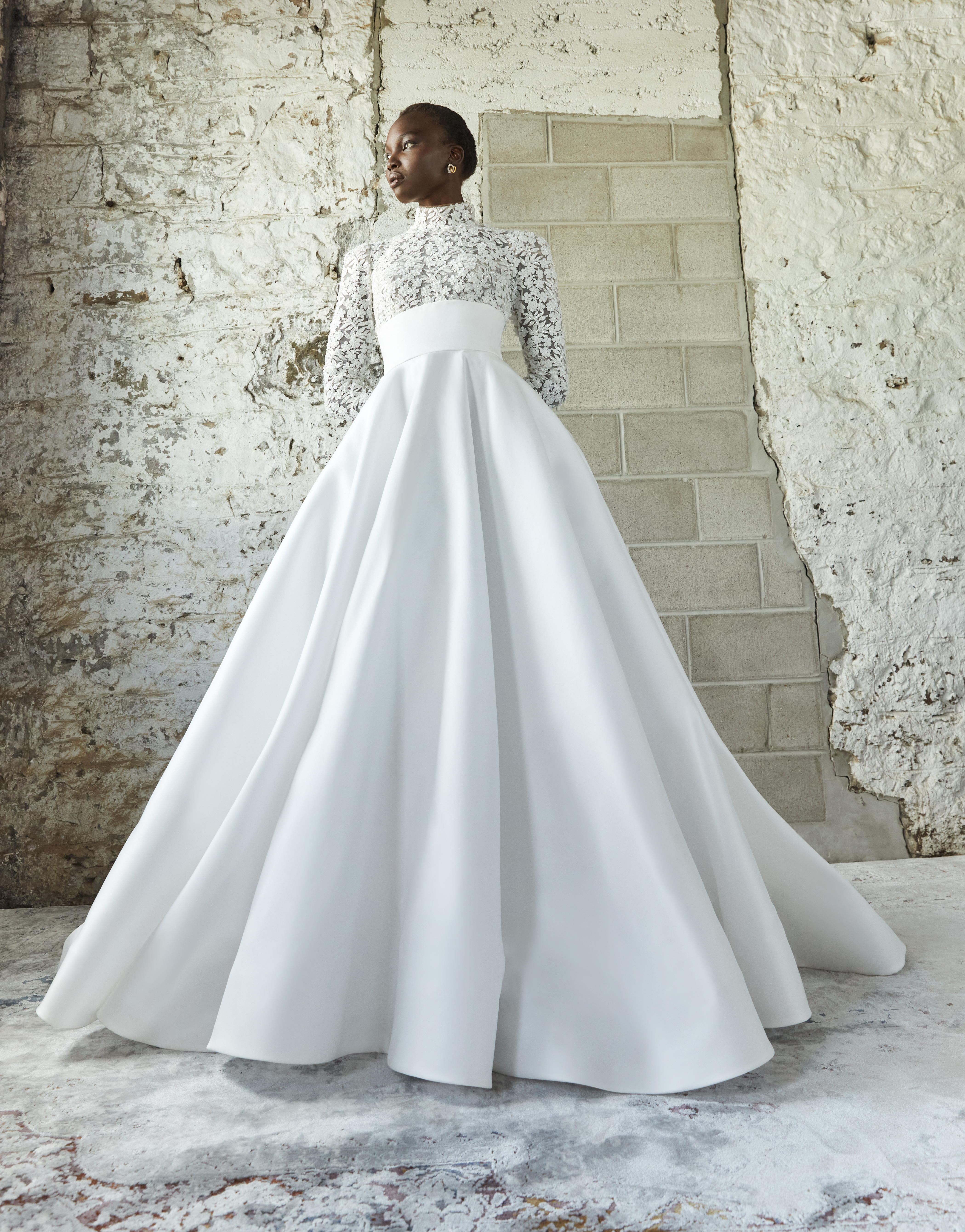 Bride wearing the Thyra ballgown from the front, showing the beaded lace sleeves, empire bodice, pockets, and full train.